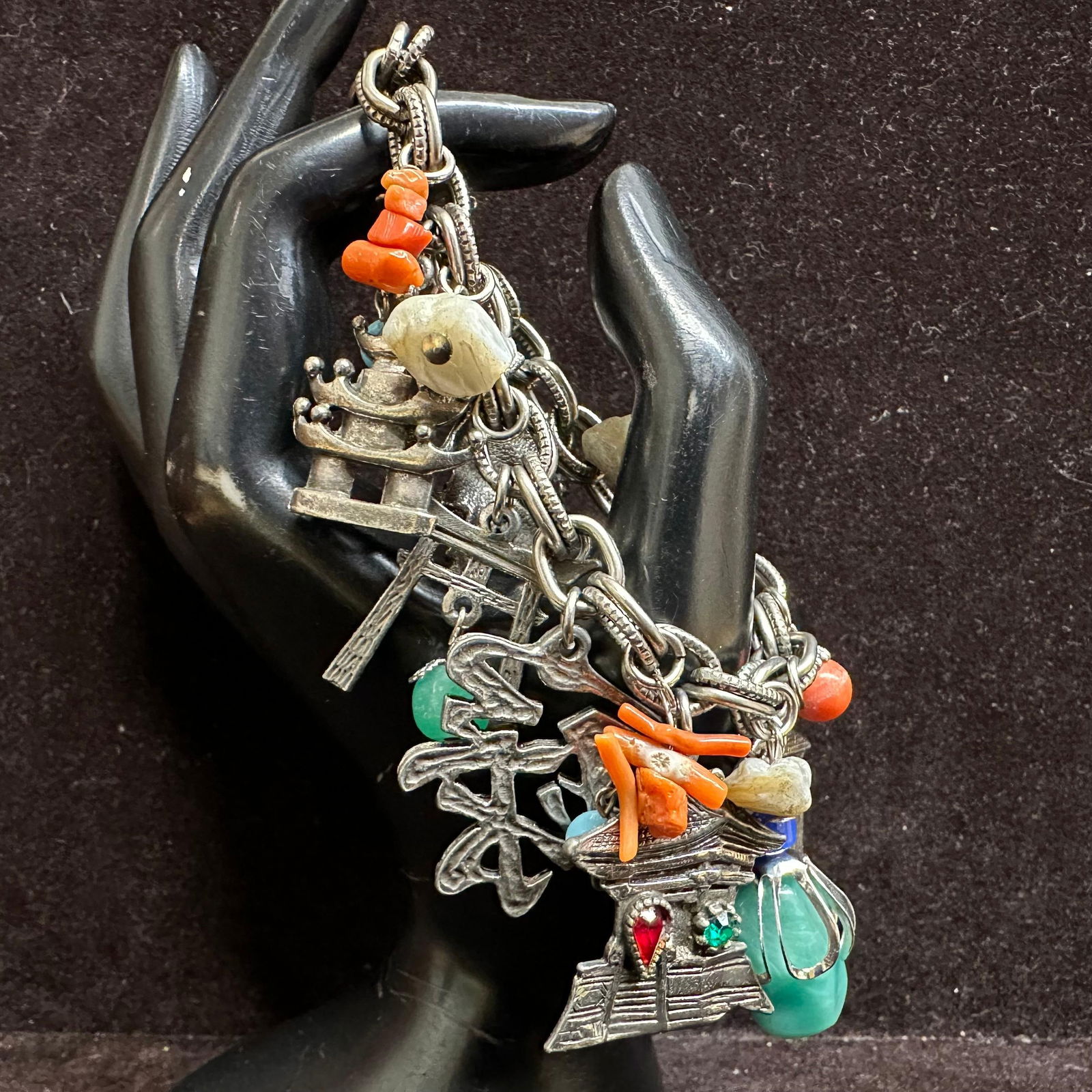Asian Theme Charm Bracelet with Mixed Stone and Metal Symbol Charms: Heavy link charm bracelet featuring Asian-inspired motifs, including pagoda, Buddha figure, Chinese coin, character symbols, lantern, and architectural elements. Includes carved green stone pendant an