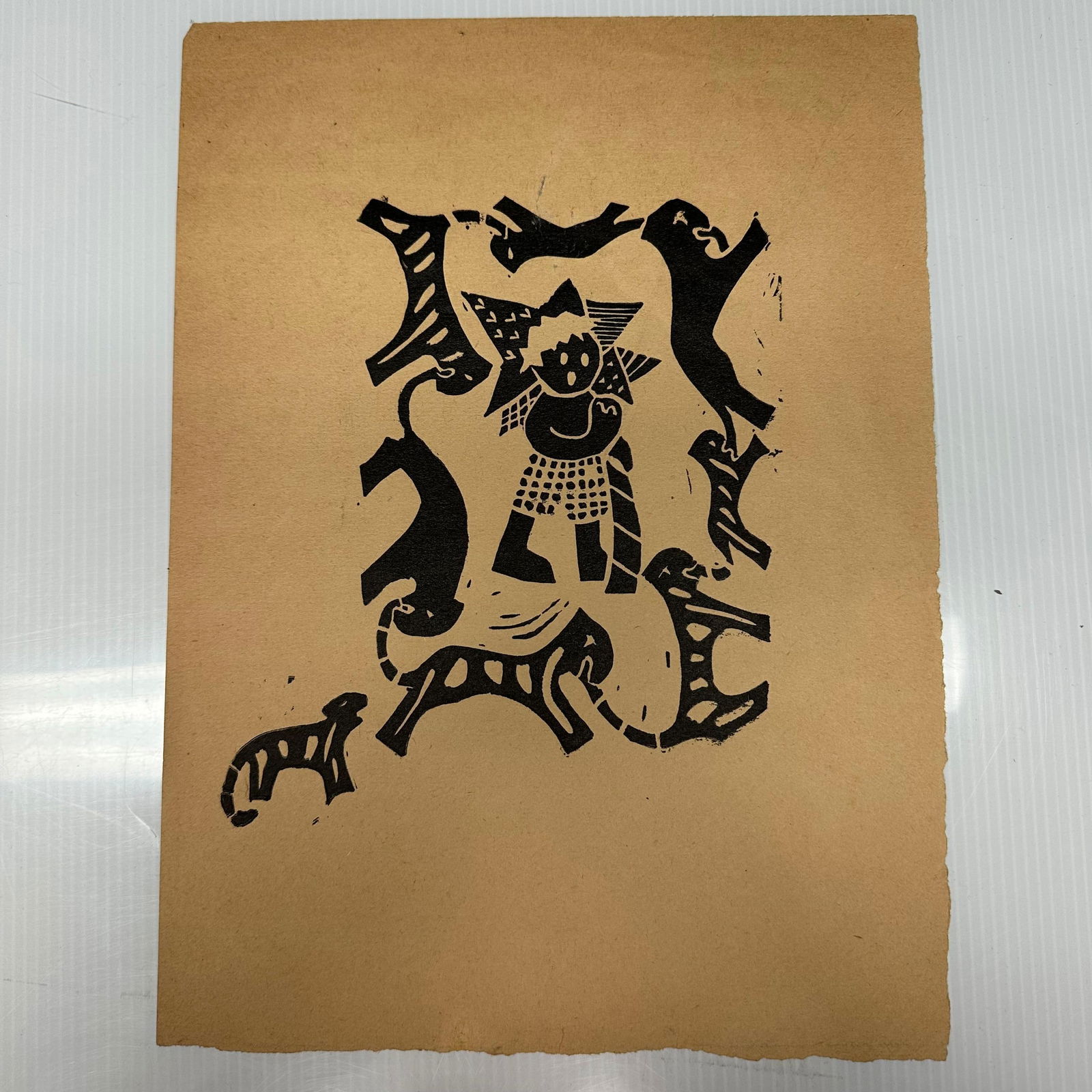Folk Art Style Linocut Print with Figure and Animal Motifs: Folk art style linocut or block print on paper depicting a central figure surrounded by stylized animal forms, with an additional small animal figure printed separately near the lower left. Executed