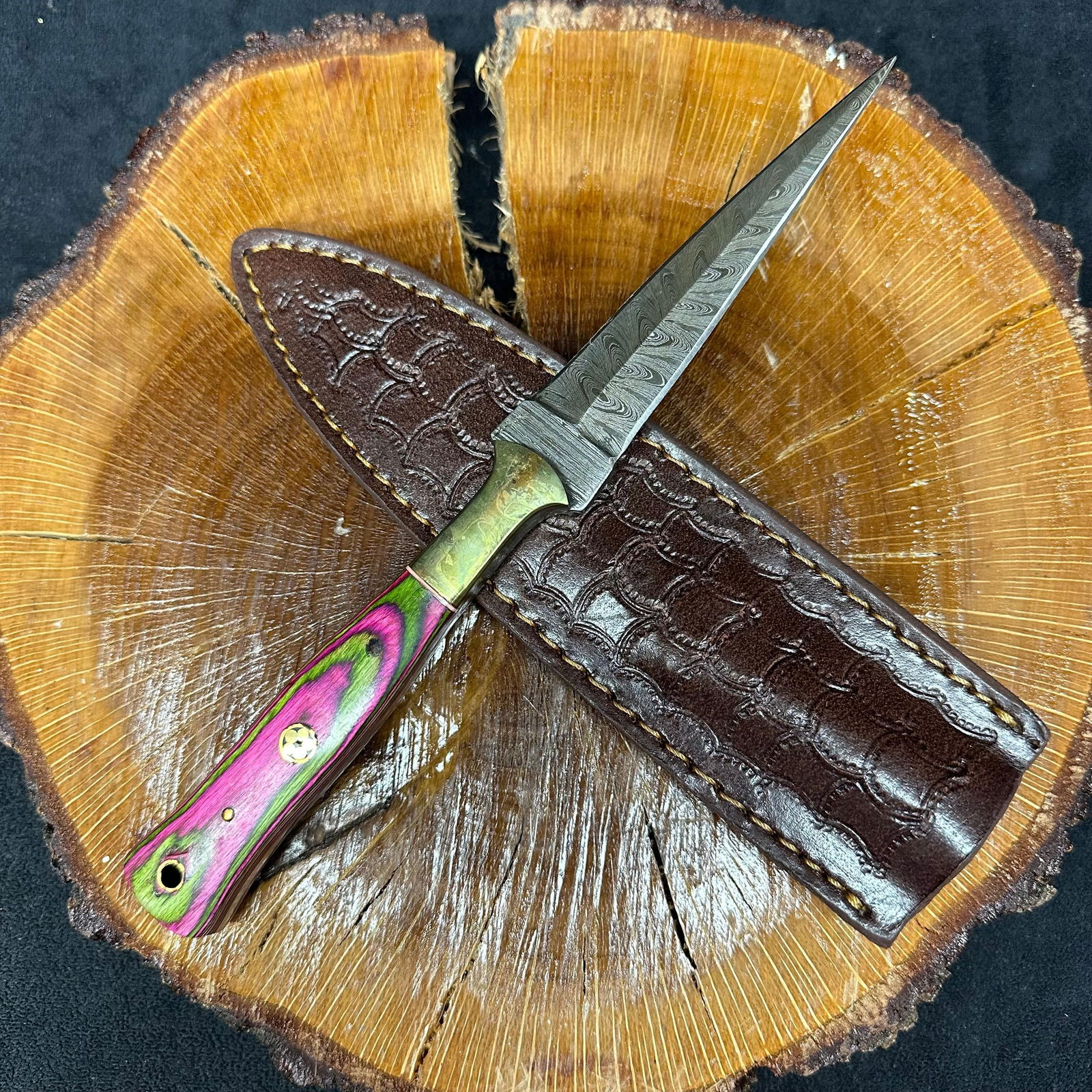 Pink Fixed Blade Knife Needle Point Dagger Style MHS Cutlery Q24: Fixed dagger-style blade knife by MHS Cutlery featuring a layered patterned steel blade and decorative spine work. The handle has a contoured, multi-colored wood/epoxy resin-style grip with metal mosa