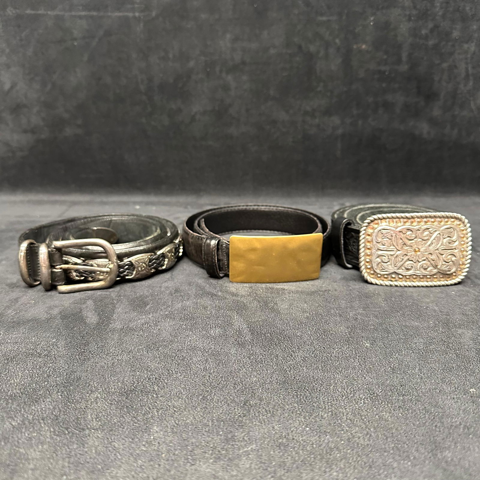Three Leather Belts with Decorative Buckles Justin Tooled Leather and Western-Style Buckles: Group of three leather belts featuring decorative metal buckles. Includes one Justin brand leather belt marked Justin Original Made in USA, with a tooled leather strap and a silver-tone buckle with en