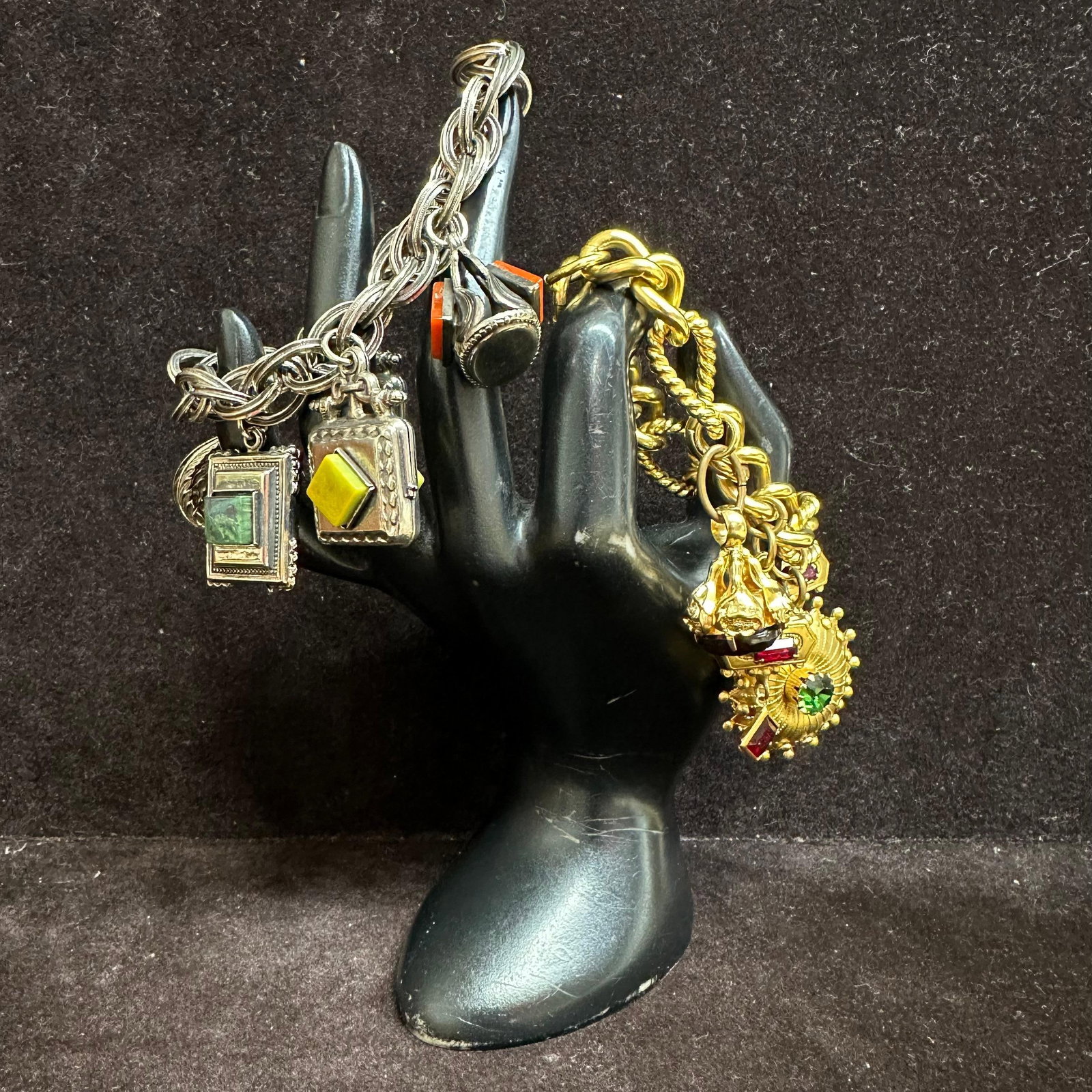 Pair of Vintage Charm Bracelets Silver and Gold Tone with Glass Stone Charms V18: A lot of two vintage charm bracelets. A silver-tone bracelet with square and geometric charms set with green and yellow glass faux stones. Includes small fob-style charm with red and black accents. He