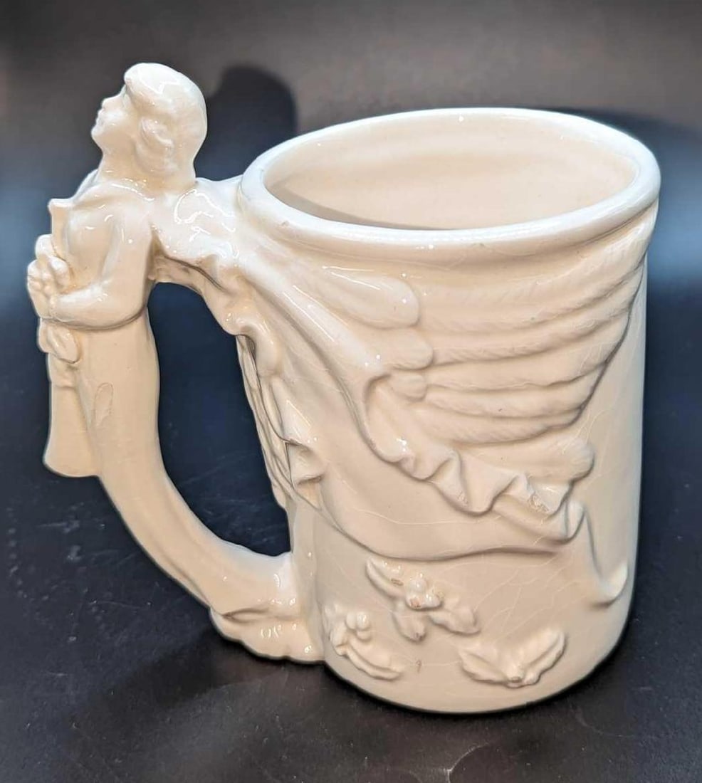 McConnell Angel Coffee Ceramic Mug: McConnell Angel Coffee Ceramic Mug. By the Talus Corp. The mug is approximately 5" x 3" x 5" and it weighs 0.68lb.. The mug is a good, used condition with crazing and small chips.