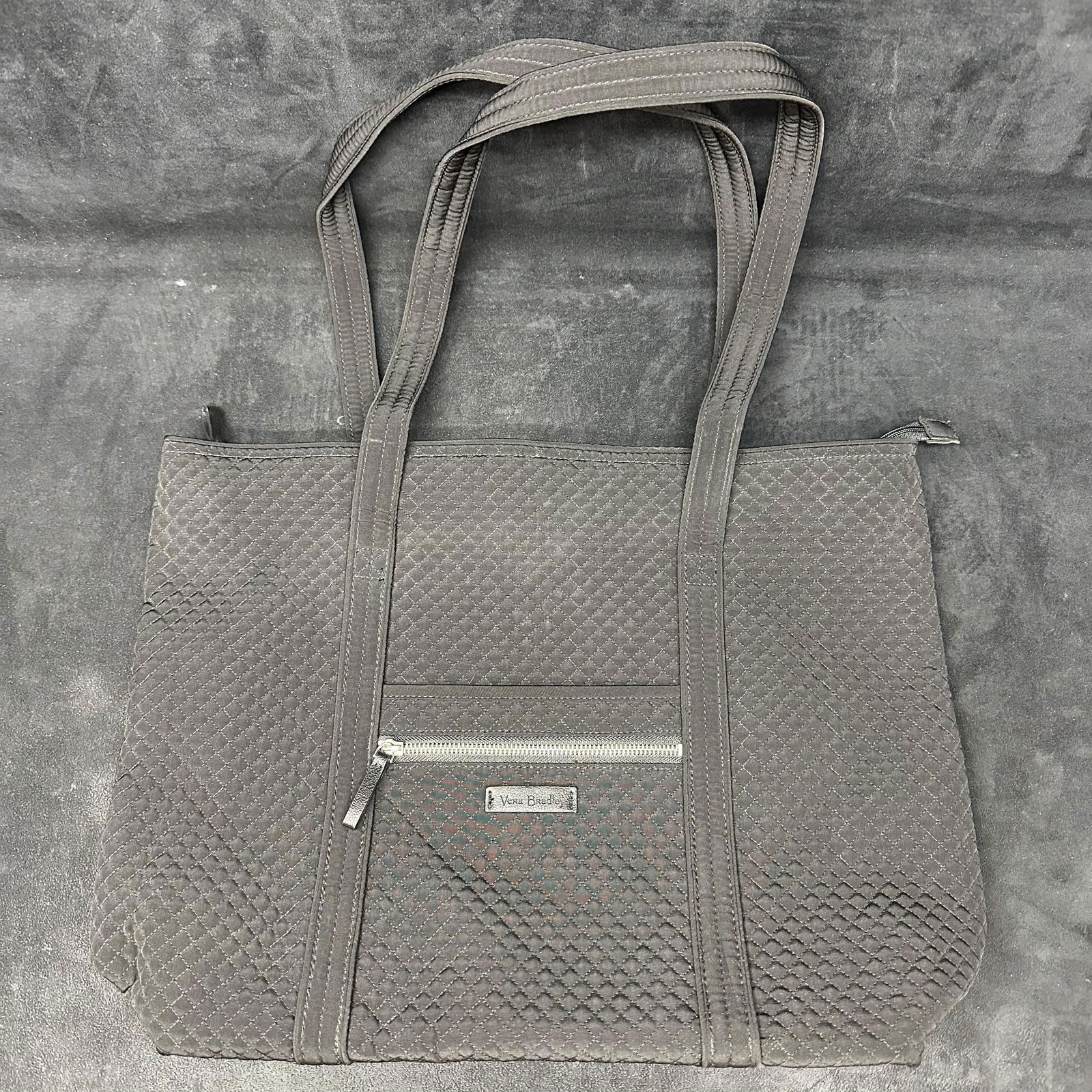 Vera Bradley Quilted Black Tote Bag with Zipper Closure: Vera Bradley quilted tote bag in solid black fabric. Features double shoulder straps, top zipper closure, exterior zip pocket, and patterned fabric interior with multiple slip pockets. This item is in