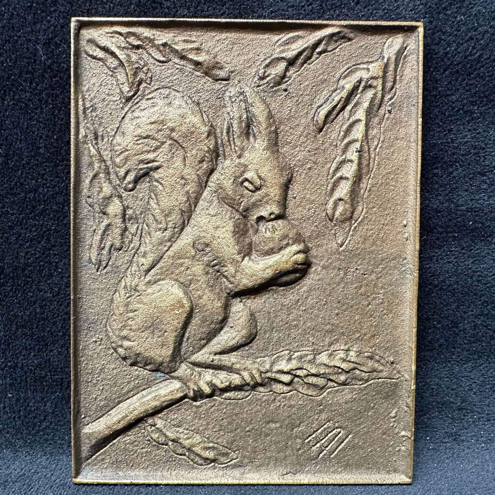 Richard Niescher Krefeld Cast Metal Squirrel Relief Plaque: Cast metal wall plaque depicting a squirrel holding a nut while perched on a branch, signed with impressed initials on the front and stamped Richard Niescher Krefeld on the reverse, rectangular form w