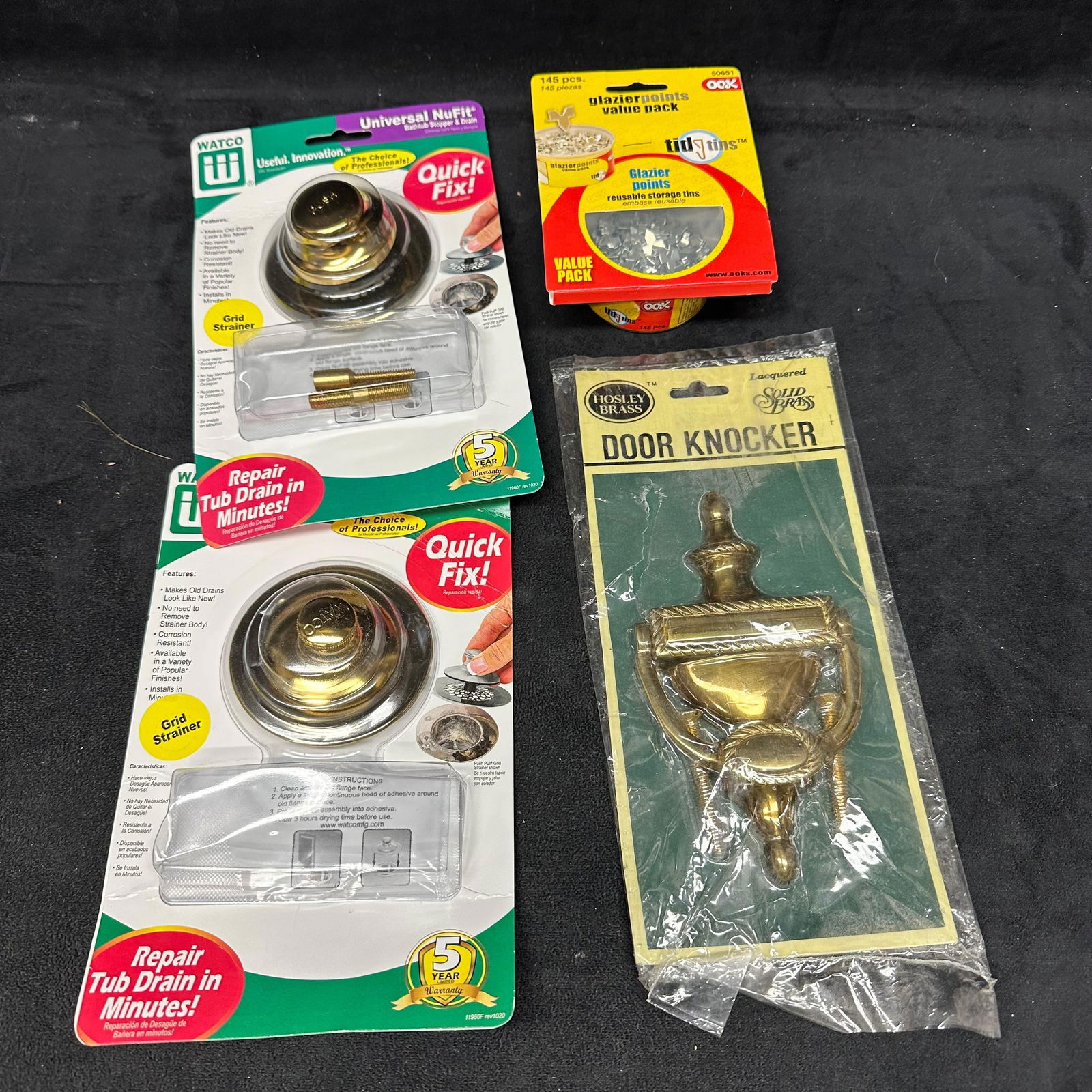 Assorted Brass Hardware and Home Improvement Lot Door Knocker Drain Closures Glazier Points: Mixed lot of brass and brass-tone home improvement hardware. Includes two Watco Universal NuFit tub drain closures in original packaging, one packaged solid brass Hosley door knocker lacquered, and on