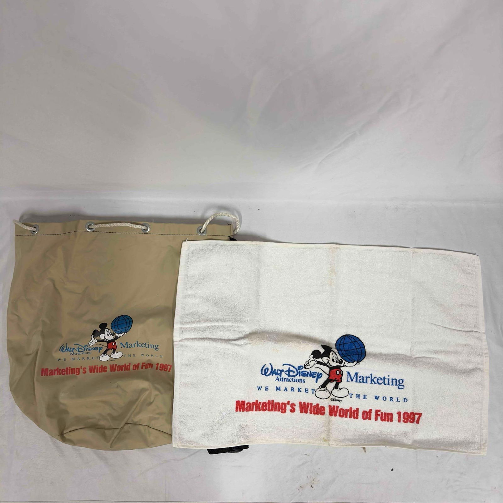Walt Disney Attractions Marketing Mickey Mouse Bag and Towel: Walt Disney Attractions Marketing Mickey Mouse Bag and Towel. The bag has one shoulder strap. These items are in good pre-owned, previously displayed condition with light wear, and surface scratches.