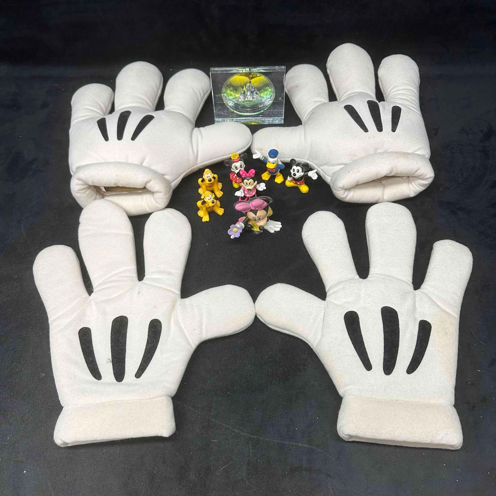 Disneyana Collectors Lot Disney Figures Mickey Glove Hands Cast Member Glass Paperweight: Mixed Disney collectibles lot including four oversized plush Mickey Mouse gloves, a set of small figurines featuring Mickey, Minnie, Donald, and Pluto, and a glass crystal cube paperweight with hologr