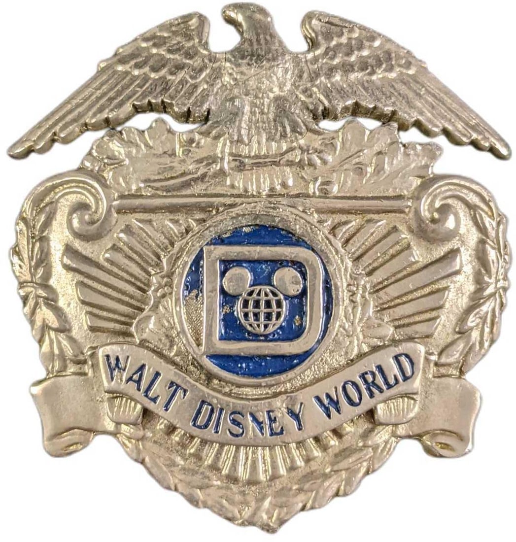 Early 1980s Disney World Female Security Hat Badge: Early 1980s Disney World Female Security Metal Hat Badge. Is approx 2" x 3/4" x 1 3/4" and it weighs under one pound at 0.06lb. The metal badge is in a good, vintage condition with some wear and scrat