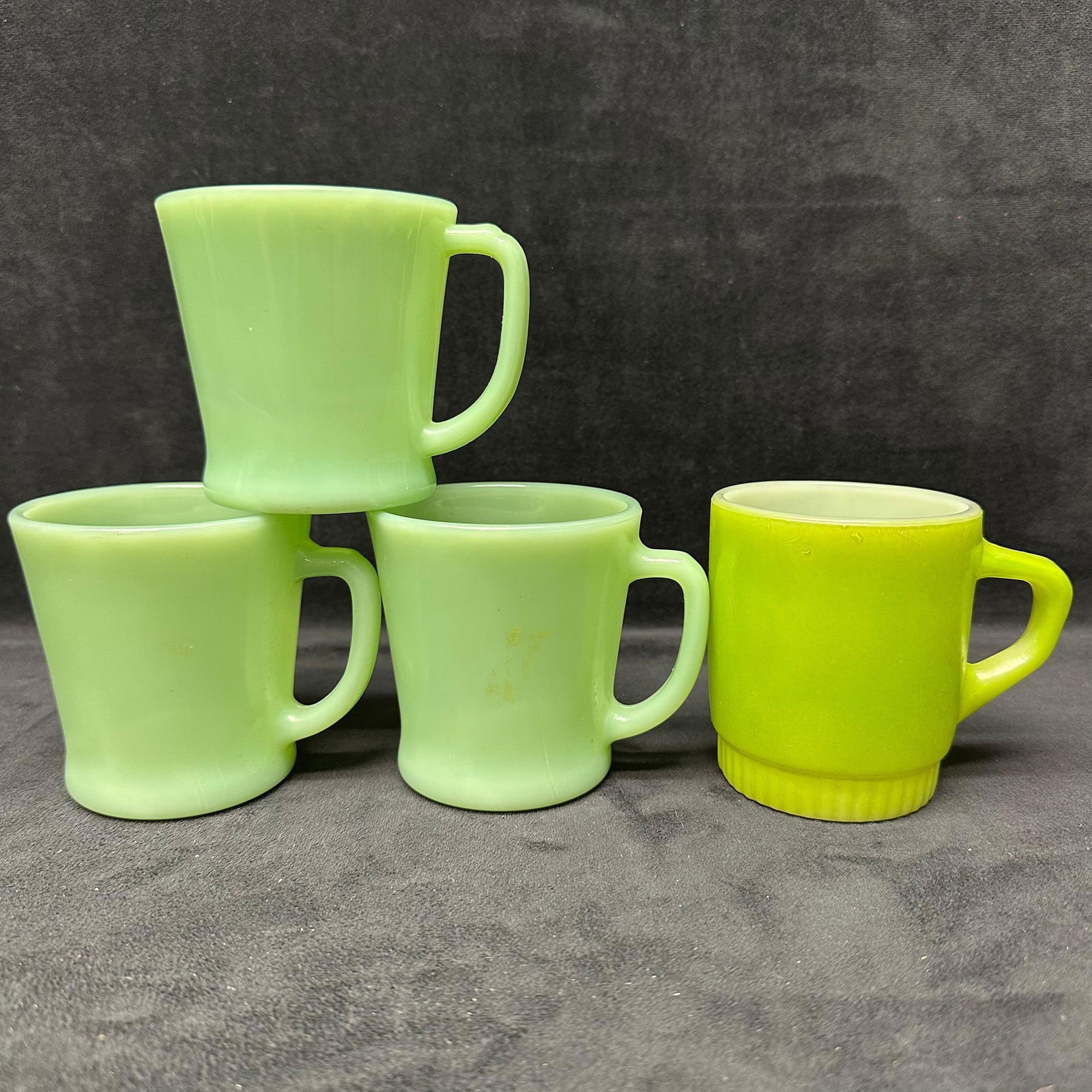 Lot of Four Vintage Fire King Jadeite Coffee Mugs Anchor Hocking Green Glassware Cups: Set of four vintage Fire King jadeite mugs by Anchor Hocking, featuring the classic 1940s - 50s pale green glass color. Three mugs are traditional D-handle styles, and one mug features a ribbed base v