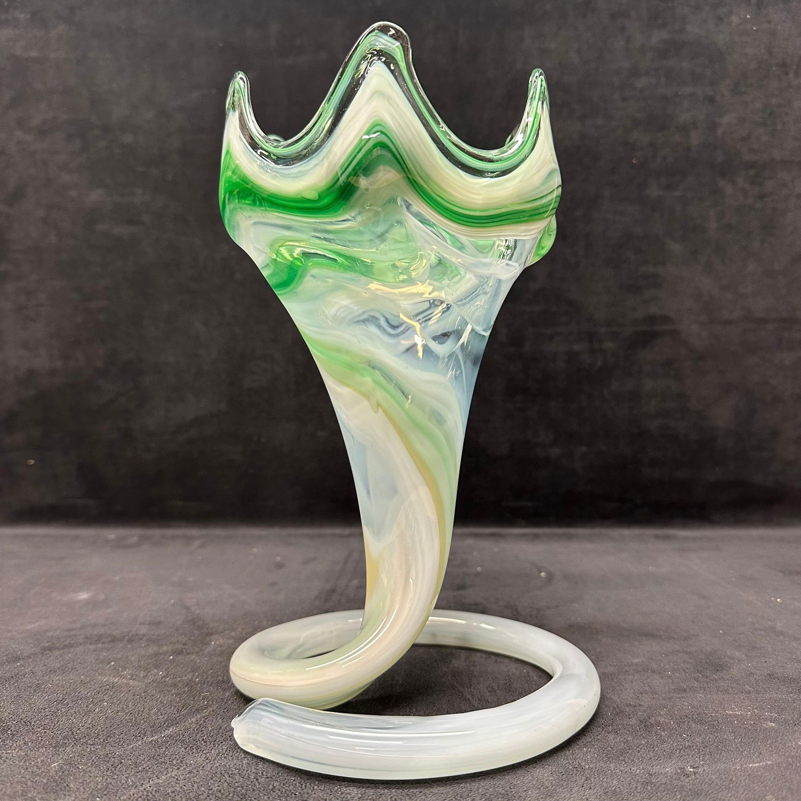 Murano Style Handblown Art Glass Tulip Vase Green and White Swirl Loop Coil Base: Beautiful hand-blown Murano-style art slag glass vase featuring a stunning green, white, and pale hue swirl pattern with clear glass accents. The piece showcases a unique cornucopia, tulip form with a