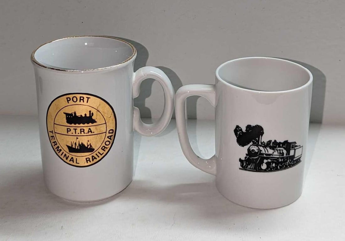 2 Vintage Port Terminal Railroad Ceramic Mugs: 2 Vintage Port Terminal Railroad Ceramic Mugs. The smaller mug is approx 4 1/4" x 2 7/8" x 3 3/4" and the larger mug is approx 4 1/4" x 3" x 4 3/8". The total weight is 1.24lb. The smaller mug has