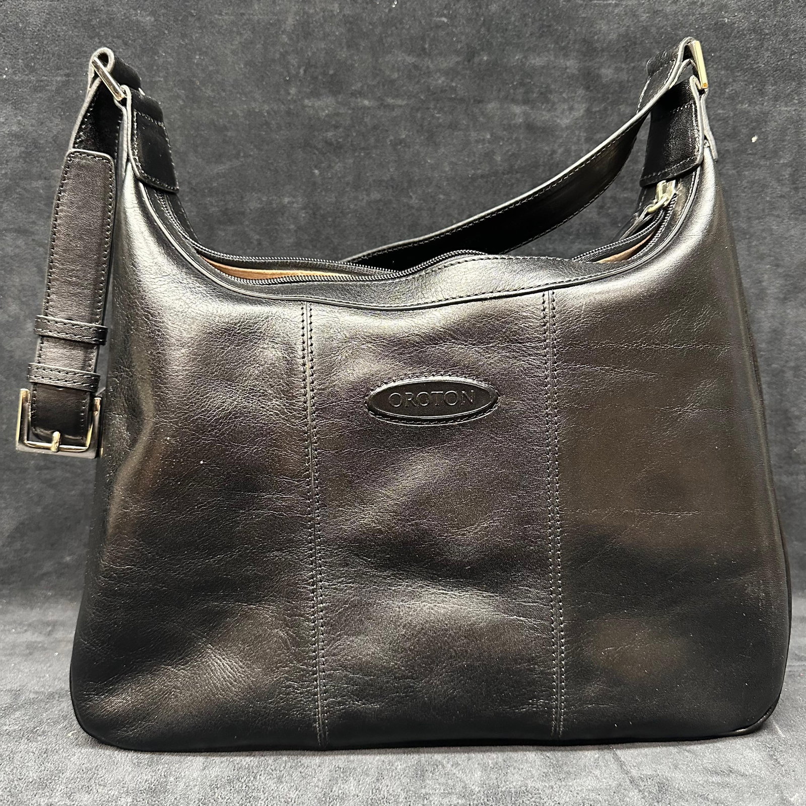 Oroton Black Leather Shoulder Bag with Adjustable Strap: Black leather shoulder bag by Oroton. Features an adjustable leather strap, top zip closure, and a zippered exterior pocket on the reverse. Interior is lined in tan suede with an additional zippered
