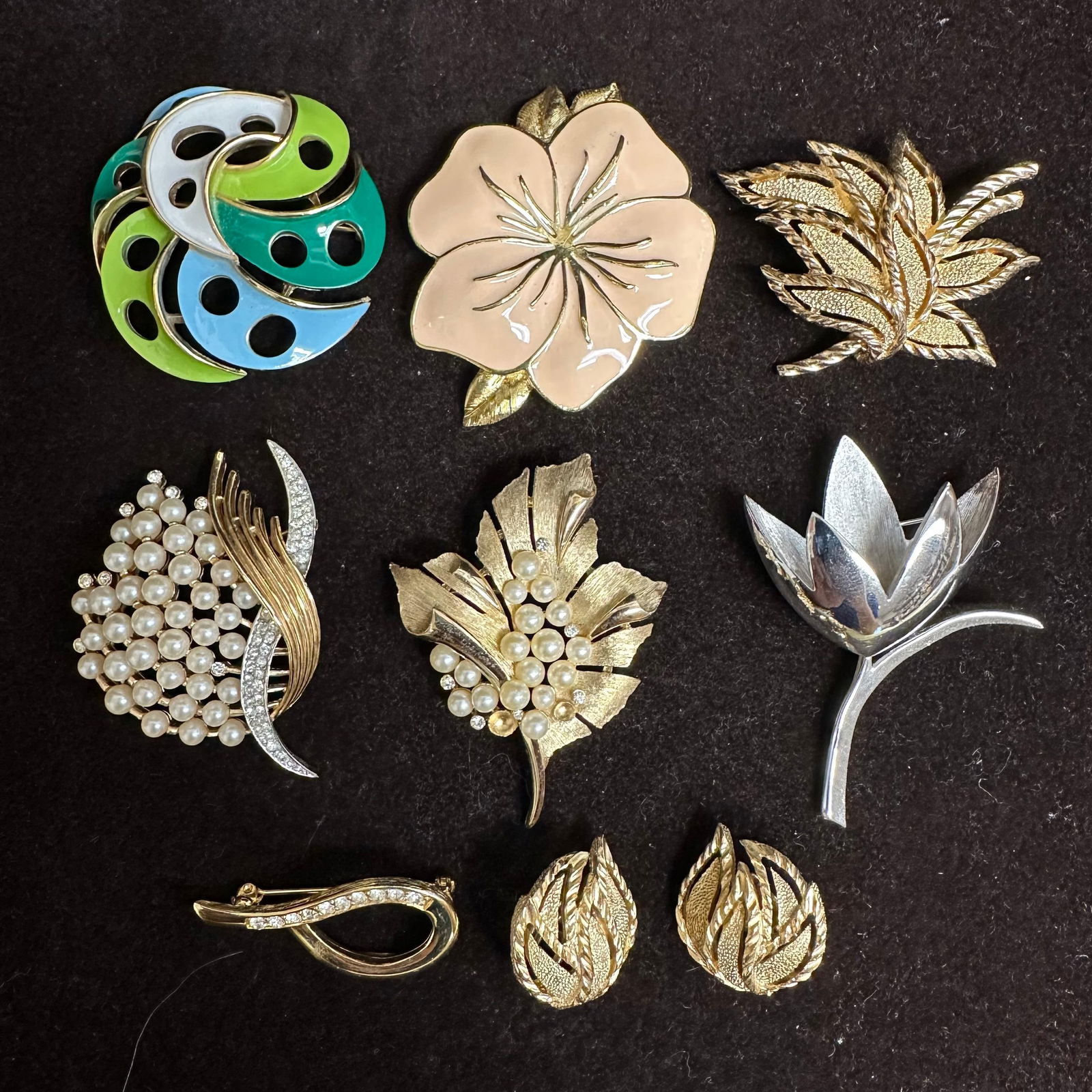Crown Trifari Costume Jewelry Brooch and Clip Earring Collection Set of Nine: Group of vintage costume jewelry pieces by Trifari, including brooches and a pair of clip-on earrings. All pieces are marked Trifari, with several bearing the crown-over-T hallmark. The lot includes