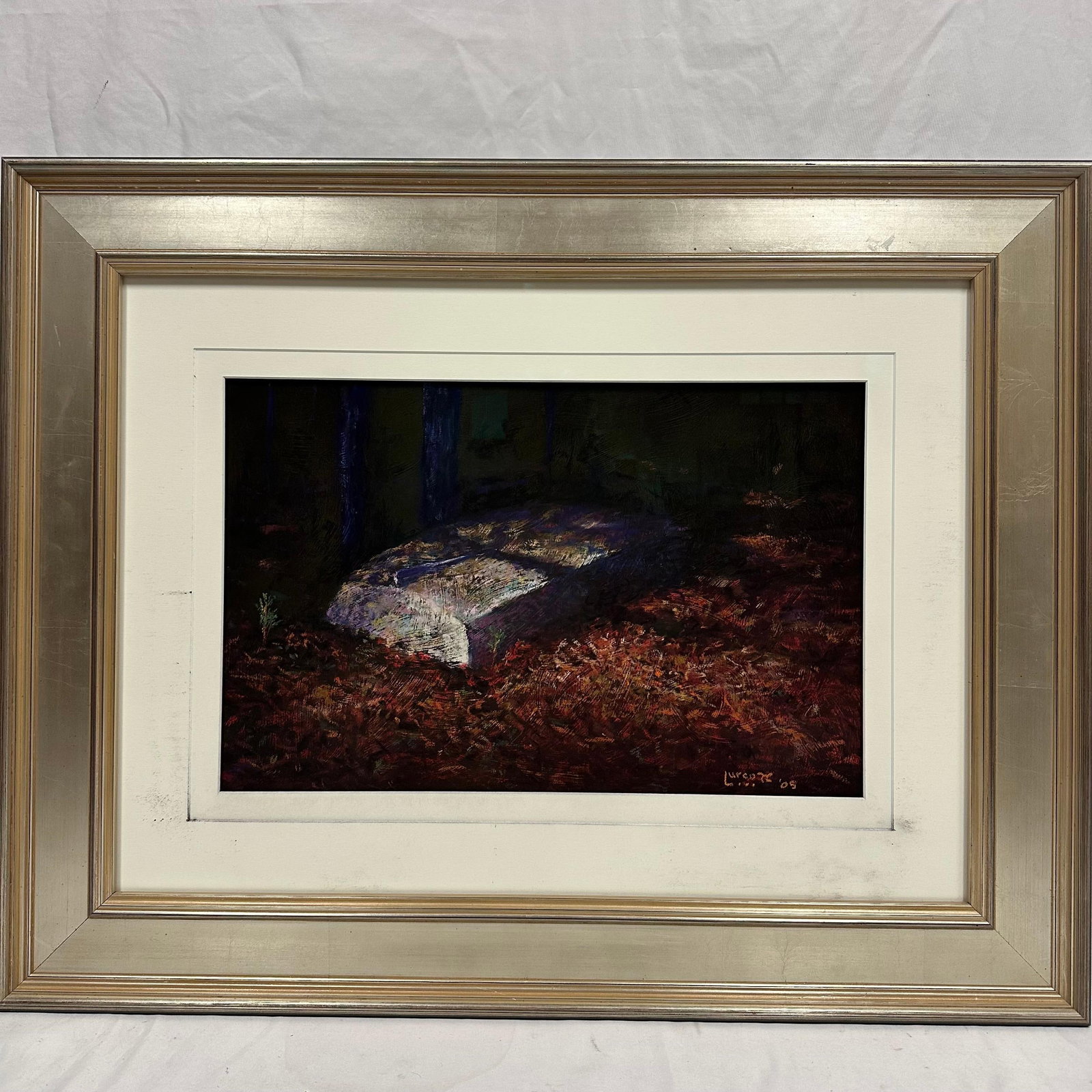 Will Lurcott Painting Tombstone in a Forest Landscape Signed and Framed: Framed original painting by artist Will Lurcott, dated 2005. The artwork depicts a stone slab in a forest clearing with dramatic lighting and deep, earthly tones. Presented in a wide silver-tone frame