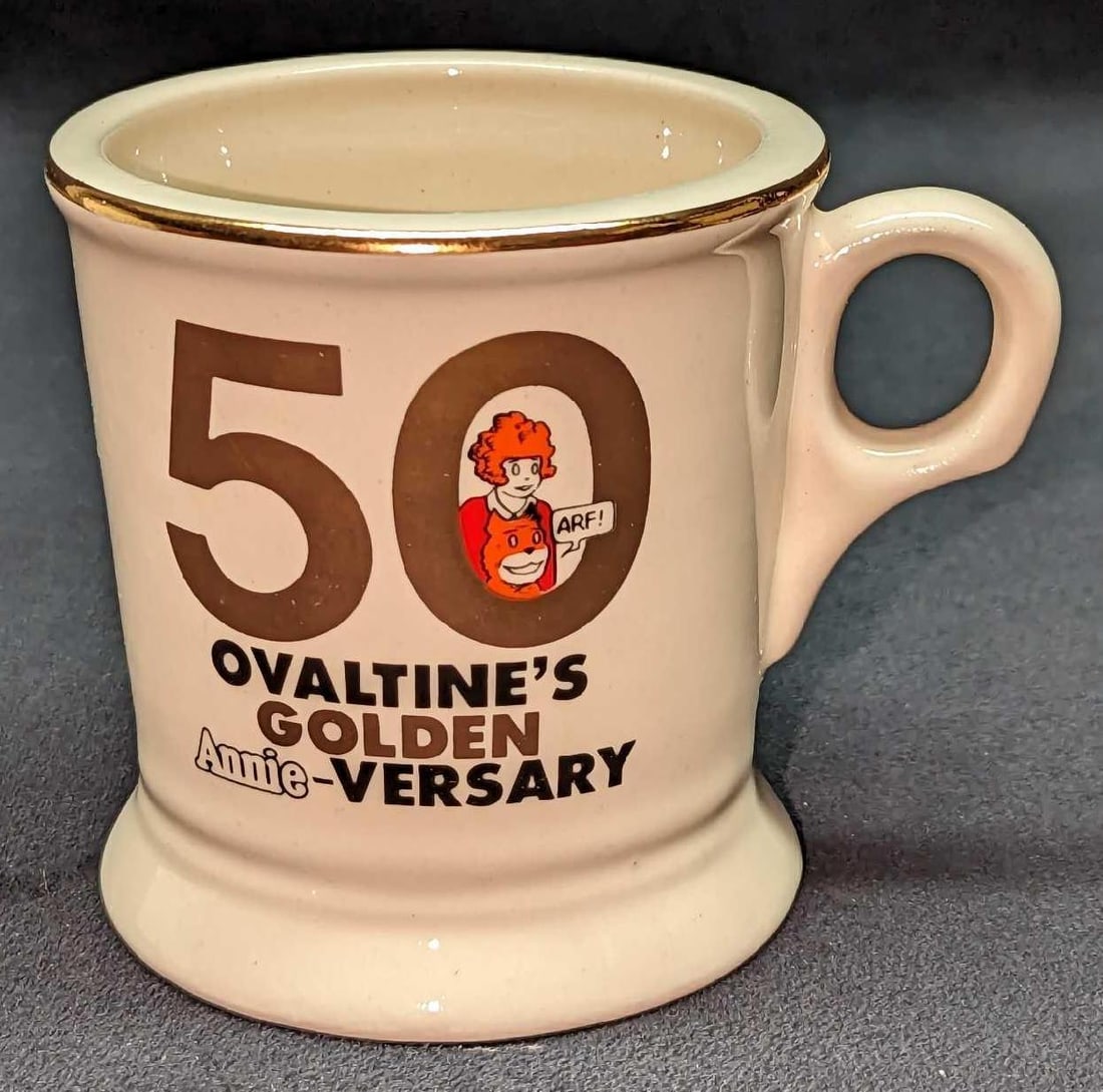 50th Ovaltine's Golden Annie-Versary Mug: 50th Ovaltine's Golden Annie-Versary Mug. This is approx 4 1/2" x 3 1/4" x 3 1/2" and it weighs 0.66lb. The ceramic mug is in good, vintage condition with no chips or cracks. This was released in 1981