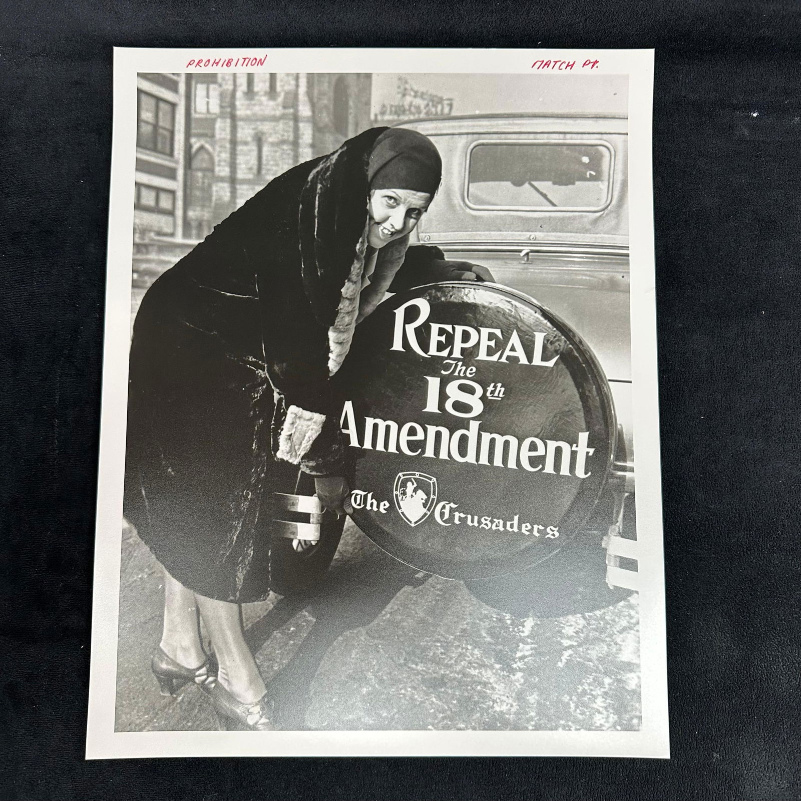 Prohibition Era Photograph Repeal the 18th Amendment Crusaders Movement Analog Photo Print: Black-and-white analog photograph capturing a woman posing beside an automobile wheel cover emblazoned with the slogan “Repeal the 18th Amendment – The Crusaders.” This powerful image
