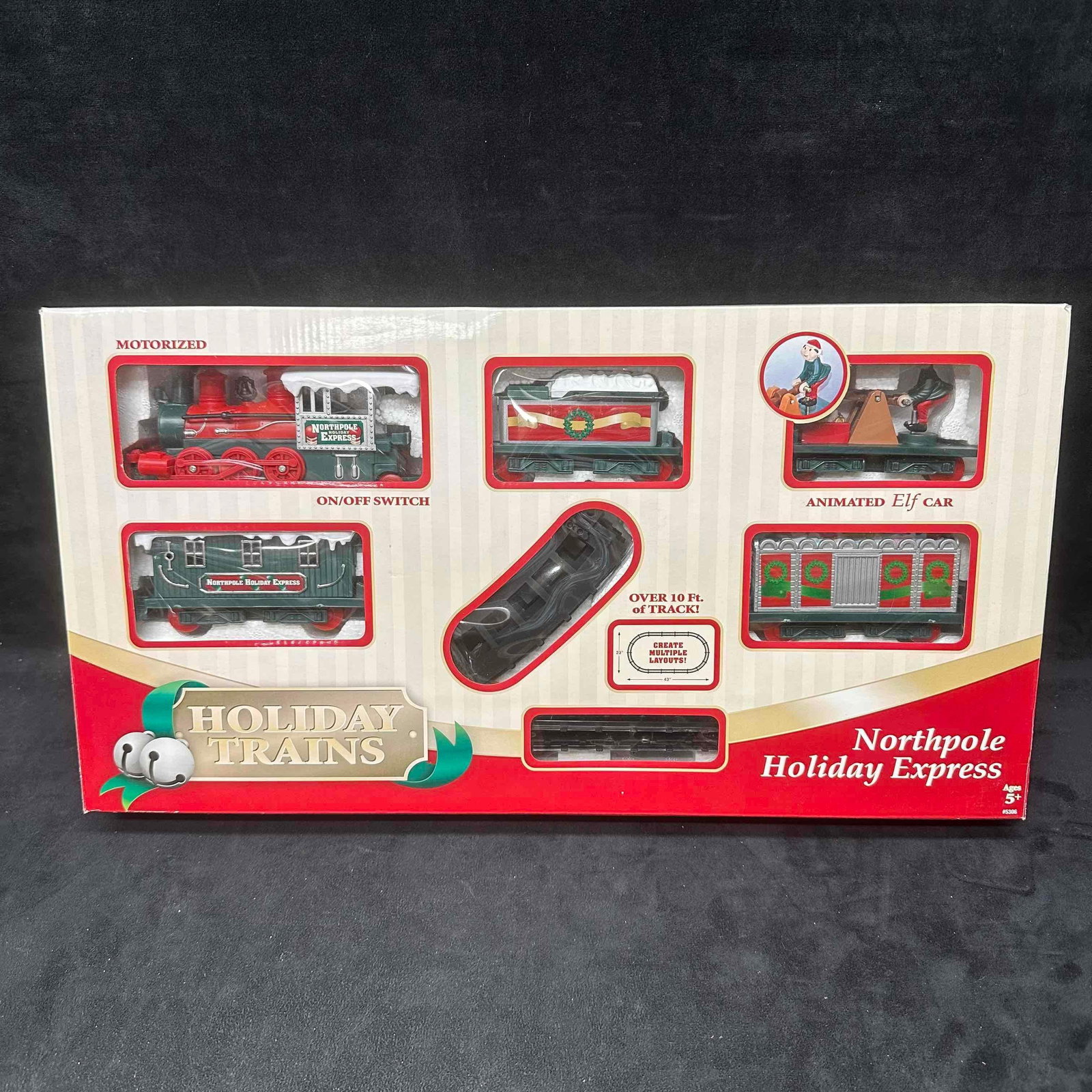 Trains Northpole Holiday Express Motorized Train Set Animated Elf Car: Holiday Trains Northpole Holiday Express motorized train set. Includes locomotive, cars, animated elf car, and over 10 feet of track. Features on/off switch and multiple layout options. Box shows ligh