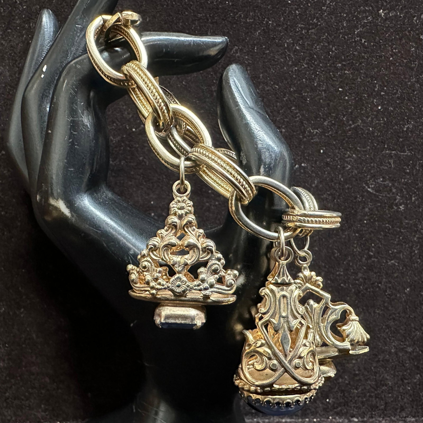 Chunky Gold Tone Charm Bracelet with Ornate Fob Charms and Colored Glass Faux Stones: Heavy gold-tone link charm bracelet featuring five ornate fob-style charms. The bracelet consists of large textured oval links with decorative detailing and a box clasp closure. All stones appear to b