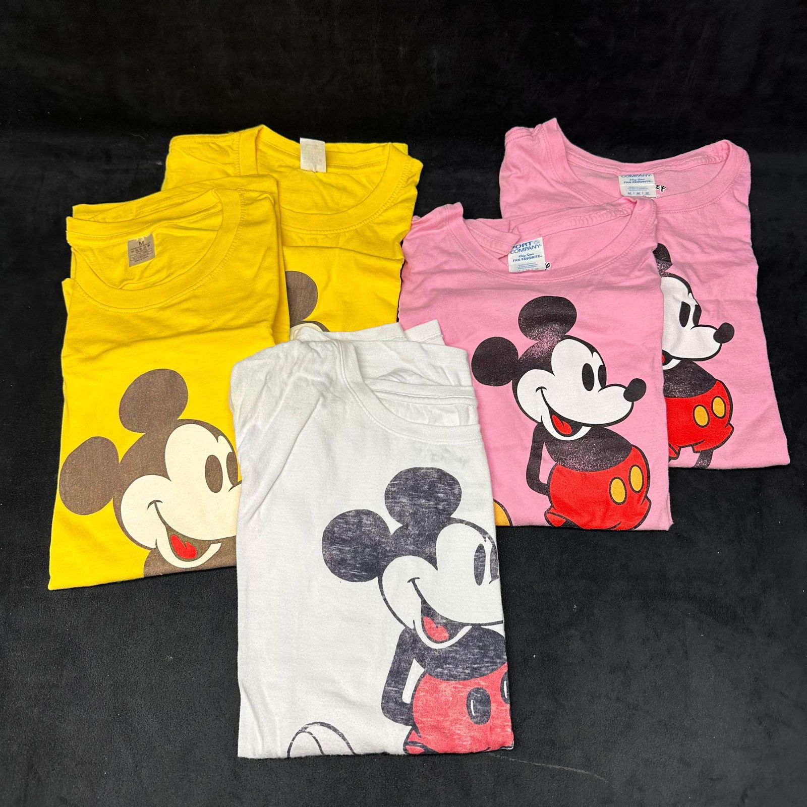 Five Disney Mickey Mouse Graphic T-Shirts Size Medium White Pink Yellow: The lot includes five Disney-branded Mickey Mouse graphic T-shirts. Assorted colors, including yellow, pink, and white, each featuring a classic Mickey Mouse design. All shirts are adult size Medium.