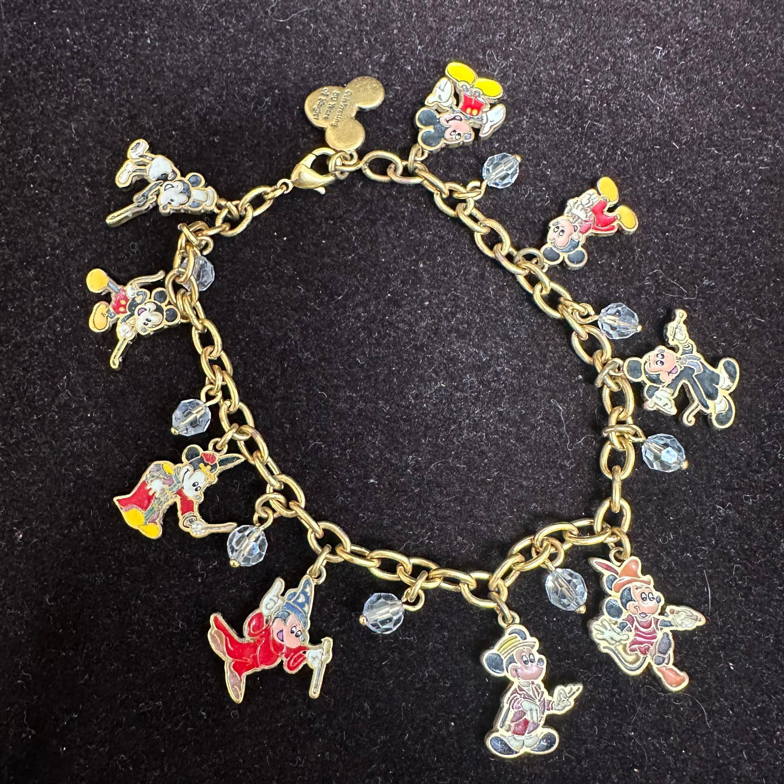 Bradford Exchange Disney Mickey Mouse Through The Years Charm Bracelet: Mickey Through the Years Charm Bracelet, exclusive from The Bradford Exchange. Gold-tone chain with enamel Mickey Mouse charms depicting his various looks through the decades, accented with clear face