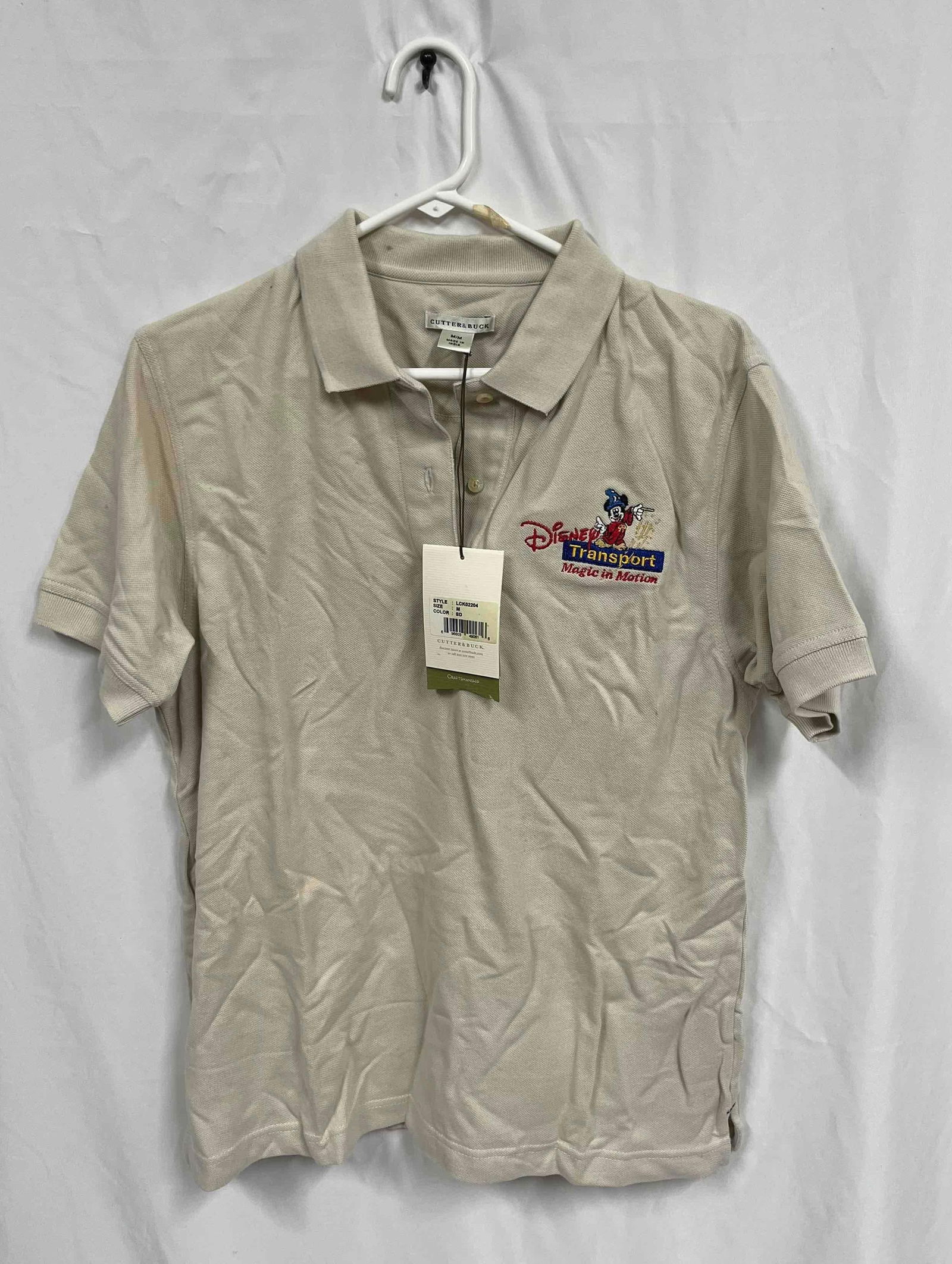 Disney Transport Magic In Motion Men's Cutter & Buck Size Medium Polo Shirt: This lot contains a Disney Transport Magic In Motion Men's Cutter & Buck Size Medium Polo Shirt. Total weight is approx 0.5lbs. Overall the shirt is in average condition as it still has the original t