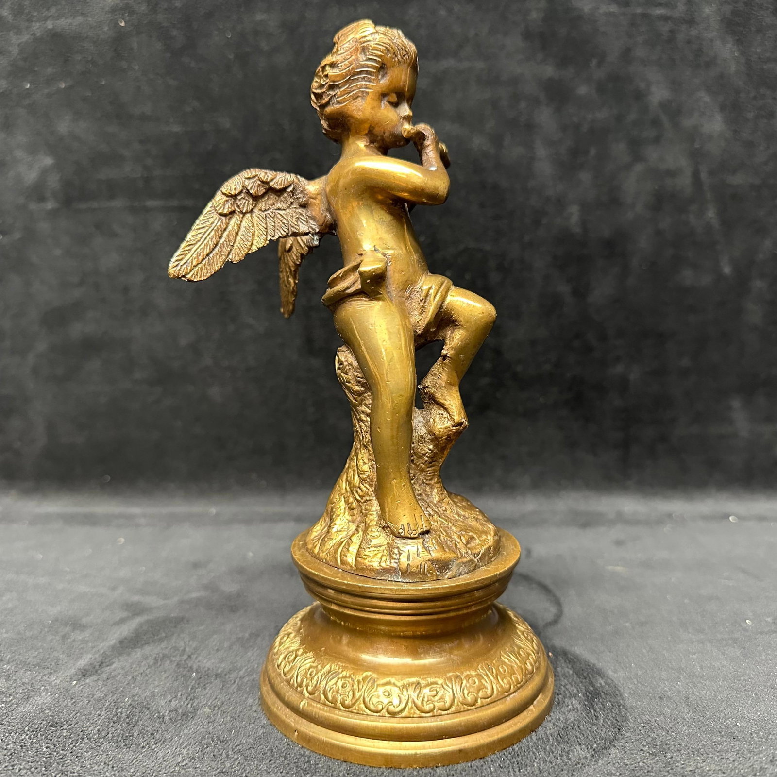 Vintage Gilt Metal Brass Cherub Figurine Playing Flute on Pedestal Base: Decorative vintage gilt metal brass figural sculpture depicting a winged cherub playing a flute, posed atop a textured pedestal base with ornate detailing. Finished in a warm gold-tone patina. Appears