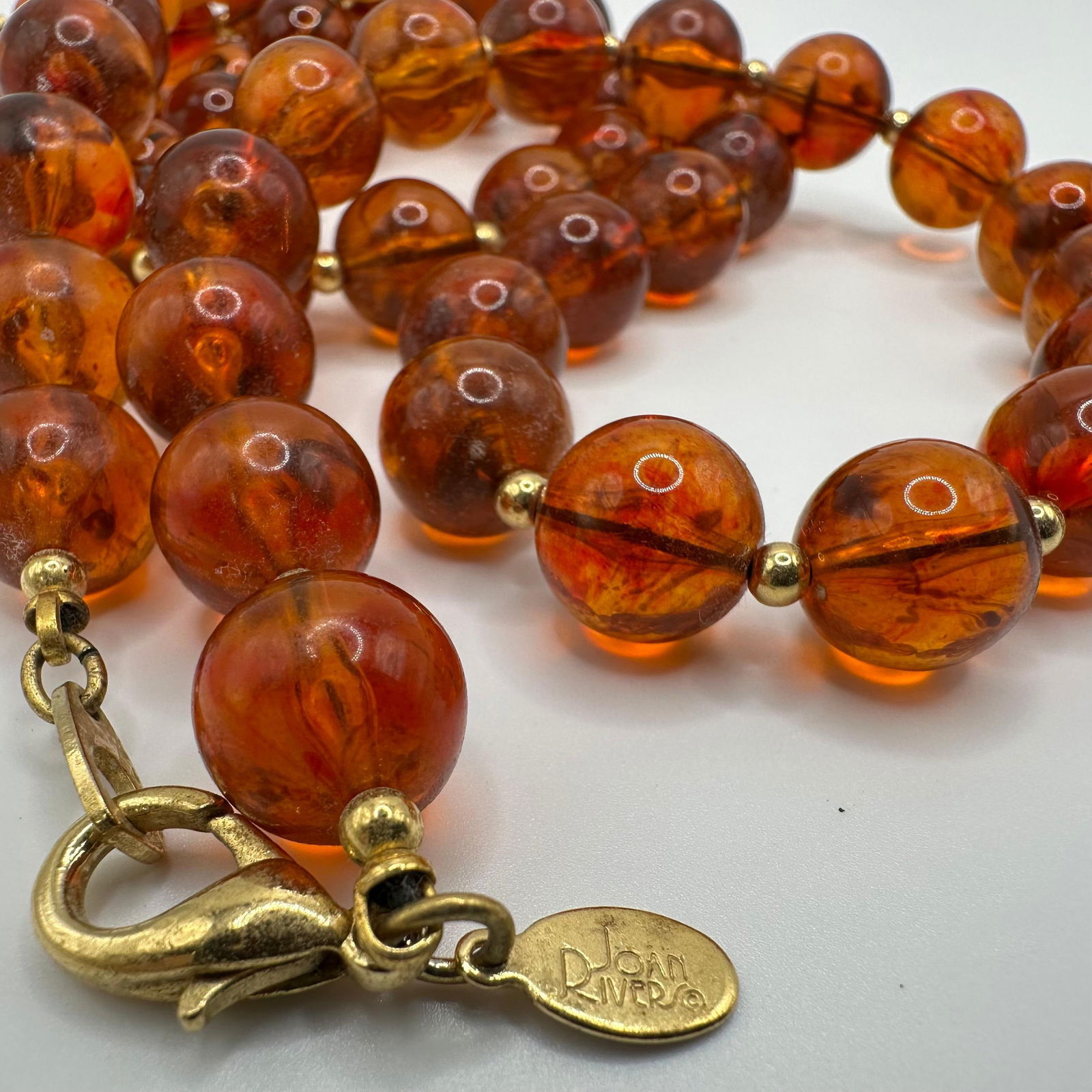 Joan Rivers Amber Colored Lucite Beaded Gold Tone Necklace: Vintage Joan Rivers lucite amber colored round beaded necklace with gold-tone accents. Joan Rivers' hallmark hang tag. This item is in pre-owned, previously displayed condition with wear and surfa