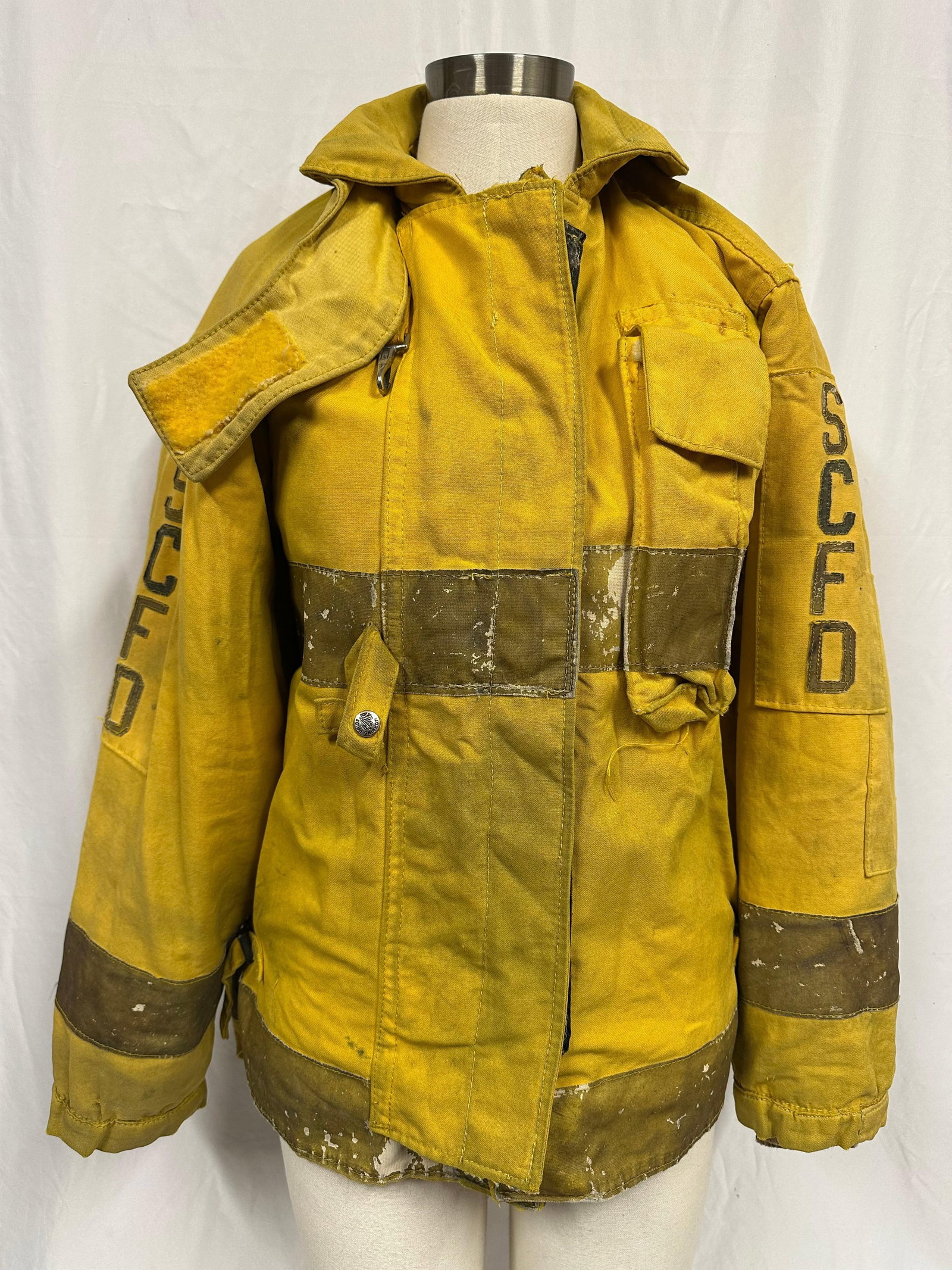 Firefighter Turnout Coat SCFD Marked Yellow Bunker Jacket with Removable Liner: Vintage yellow firefighter turnout coat marked “SCFD” on both sleeves and across the back. Traditional heavy canvas bunker coat with reflective safety striping on the chest, sleeves, and lower