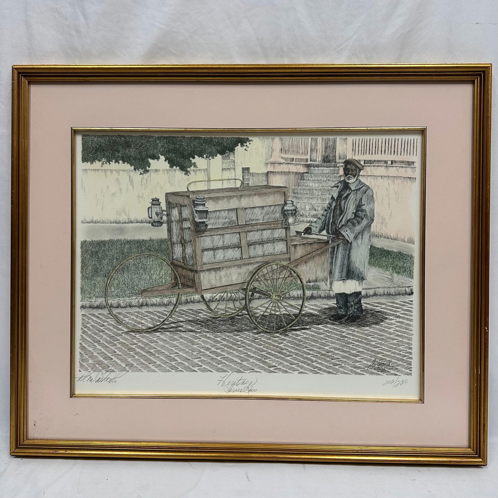 DM Carter Sr Fish Peddler Signed and Numbered Print Framed: Framed limited edition print titled Heritage Series Two by D.M. Carter Sr. Depicts a historic street vendor with a cart on a cobblestone street. Signed by the artist and numbered 202/250 in pencil. Ma