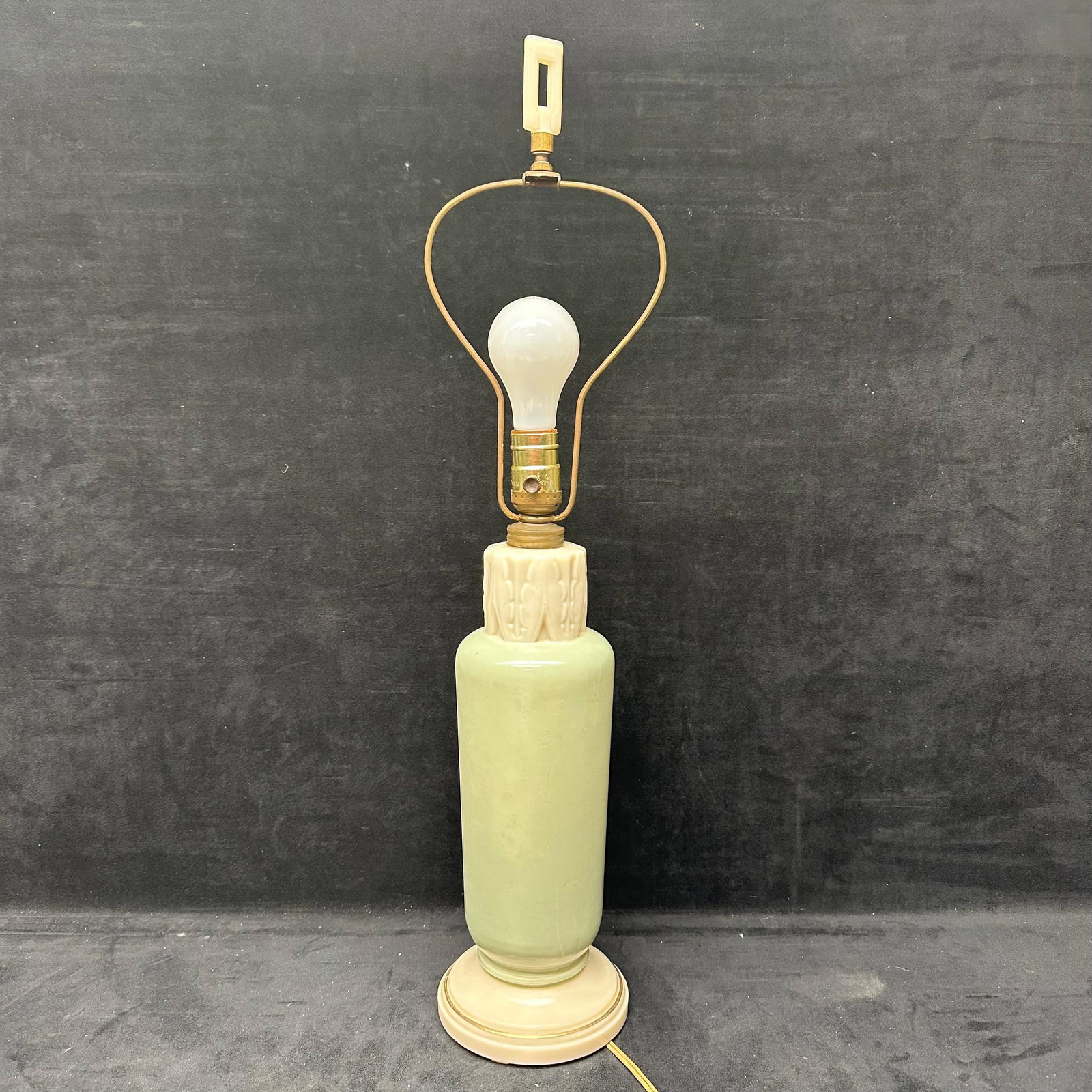 Pale Green Ivory Toned Milk Glass Porcelain Table Lamp with Carved Accent Finial: Vintage electric table lamp featuring a pale green cylindrical alabaster-style body with an ivory-toned carved upper section and matching round base. Made of milk glass porcelain. The lamp illuminates
