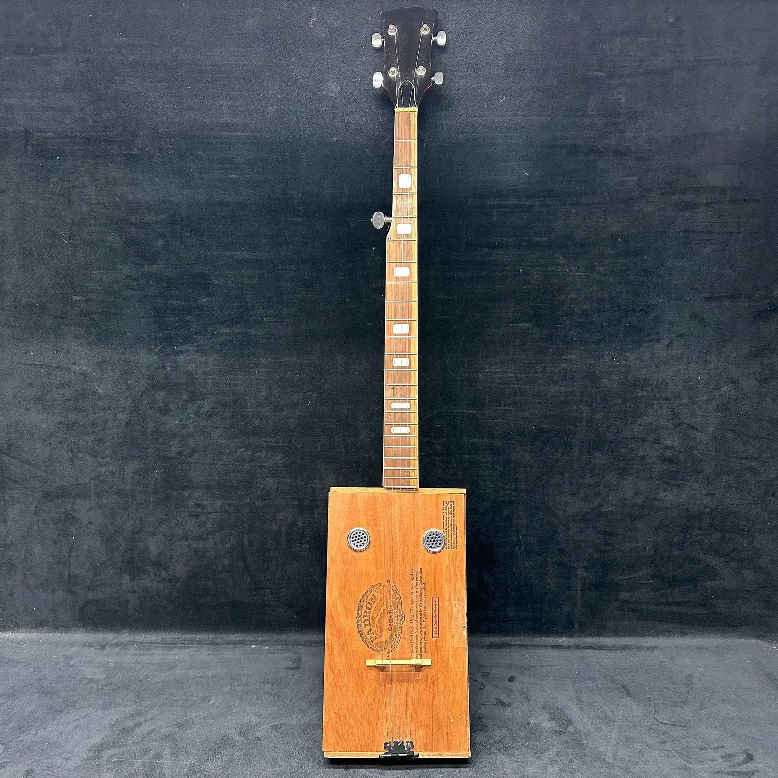 Padron 7000 Cigar Box Guitar Cigars Wooden Case Five String Folk Style Instrument Hand Crafted: Handmade cigar box guitar built using a genuine Padron 7000 wooden cigar box body. Features a full-wood neck with inlaid fret markers, five strings, metal sound hole covers, chrome tuning pegs, and a