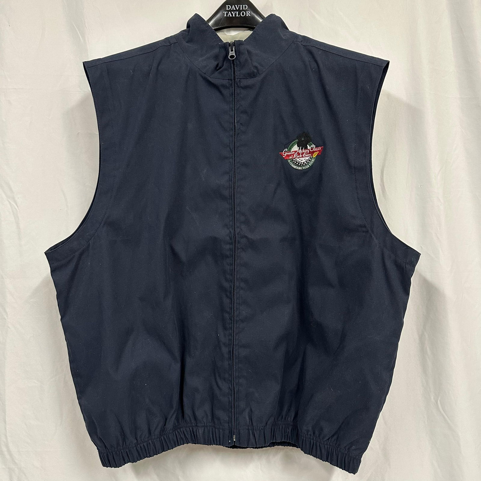Greater Hickory Classic at Rock Barn Sleeveless Zip Front Vest XL: Sleeveless zip-front vest featuring embroidered Greater Hickory Classic at Rock Barn logo on the chest. Navy blue exterior with elasticized hem and mesh interior lining. Shell is 100% polyester, made
