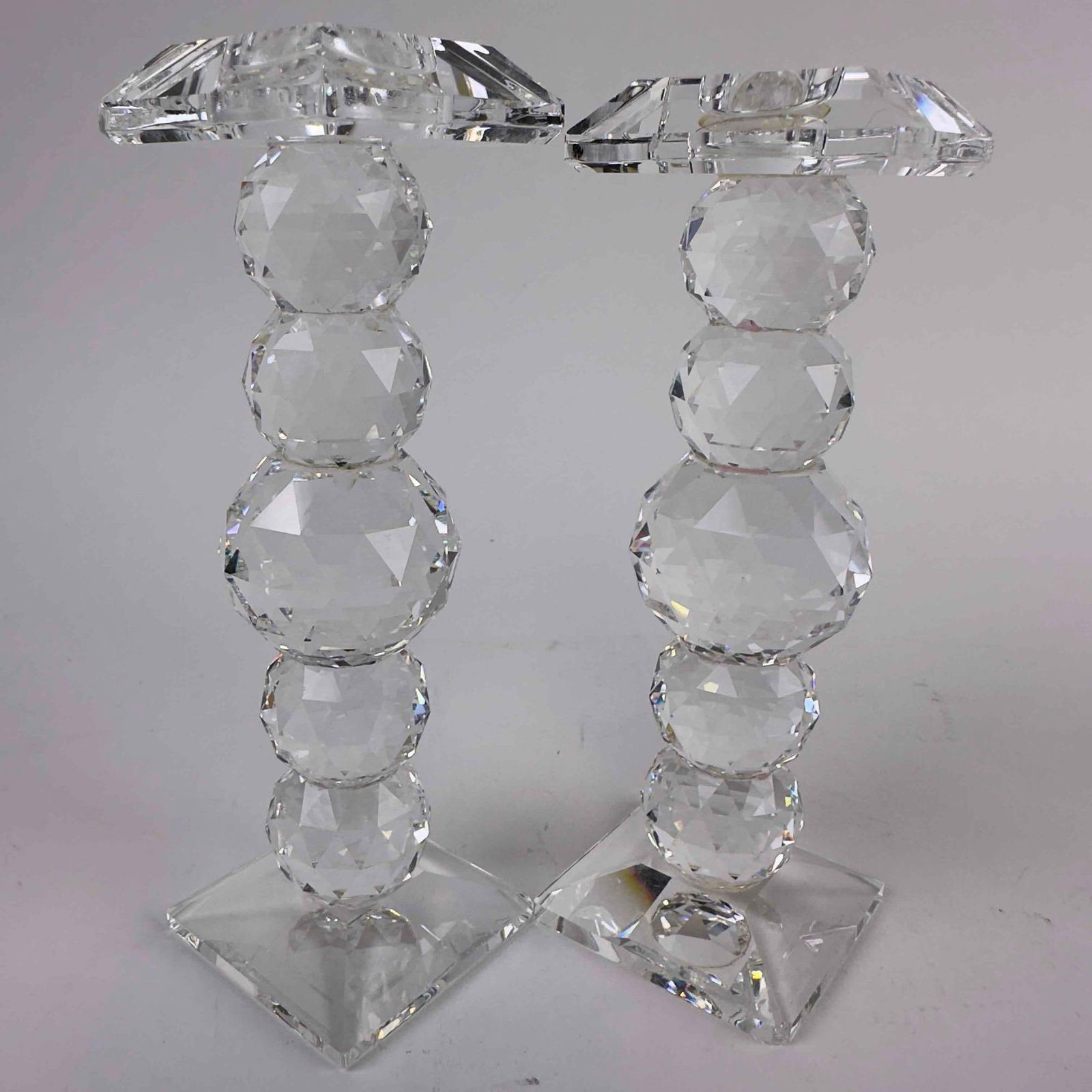 Swarovski Glass Crystal Ball Stacked Faceted Sphere Column Candle Holder Set: Swarovski 6 Inch Crystal Ball Stacked Faceted Column Candle Holder Set Retired. Pair of Swarovski crystal candle holders featuring stacked, faceted spheres on square bases. The clear crystal construct