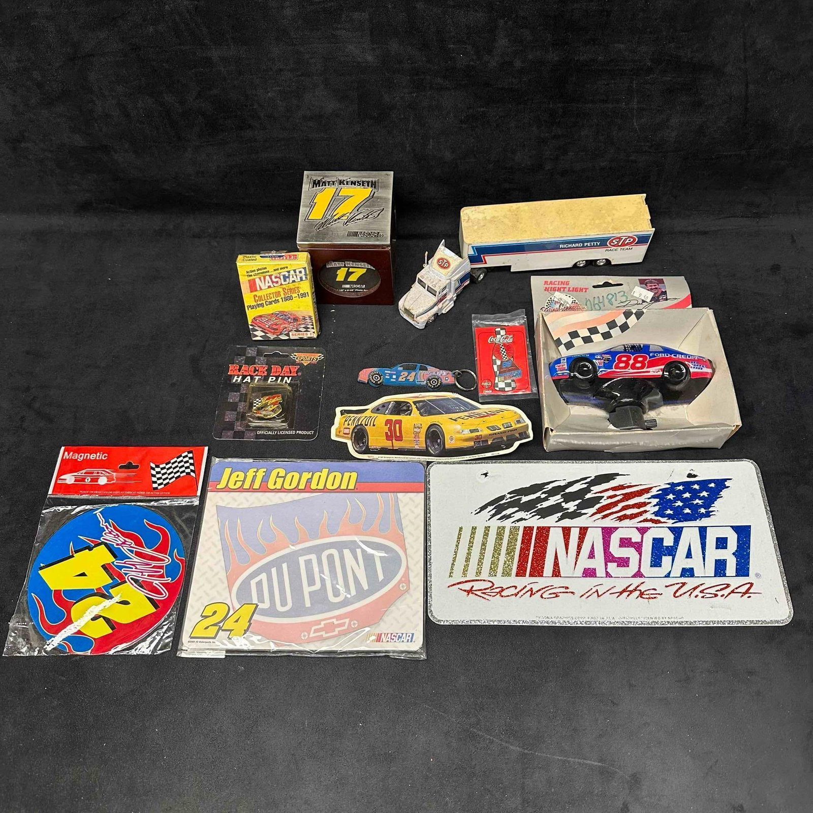 NASCAR Collectibles Souvenirs and Memorabilia Collection: Mixed lot of NASCAR collectibles including a Richard Petty STP truck and trailer, Matt Kenseth #17 display cube, NASCAR Collector Series playing cards (1980–1991), Race Day hat pin, Jeff Gordon #24