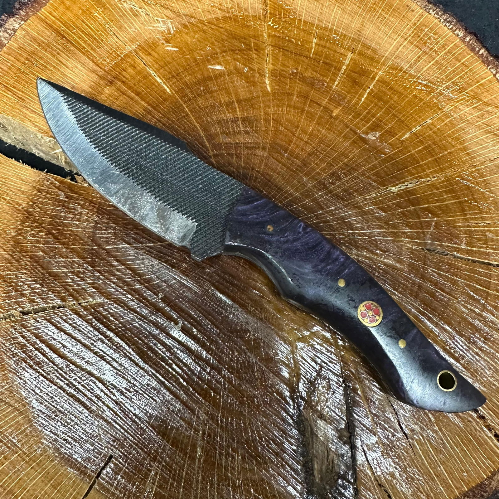 MHS Cutlery Dark Purple Black Curved Handle Textured Steel Blade Knife: Fixed blade knife by MHS Cutlery featuring a patterned textured steel blade. The handle features a curved, contoured, purple-colored wood/epoxy resin-style grip with metal mosaic pin accents. Includes