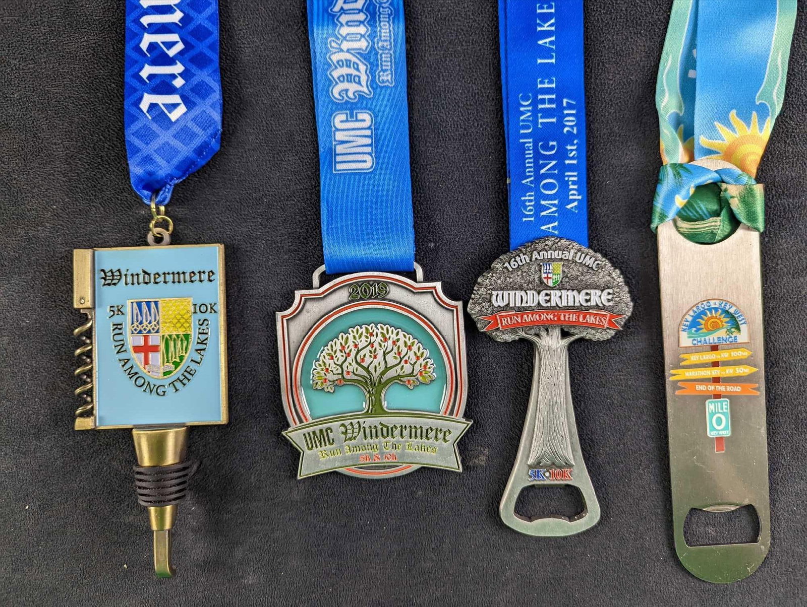 JB Four Windermere Key West Marathon Medals: This lot includes: (1) 2018 Windermere 5K/10K Run Among The Lakes Medal. Is approx 2 1/2" x 22". (1) 2019 Windermere 5K/10K Run Among The Lakes Medal. Is approx 3 1/4" x 20". <