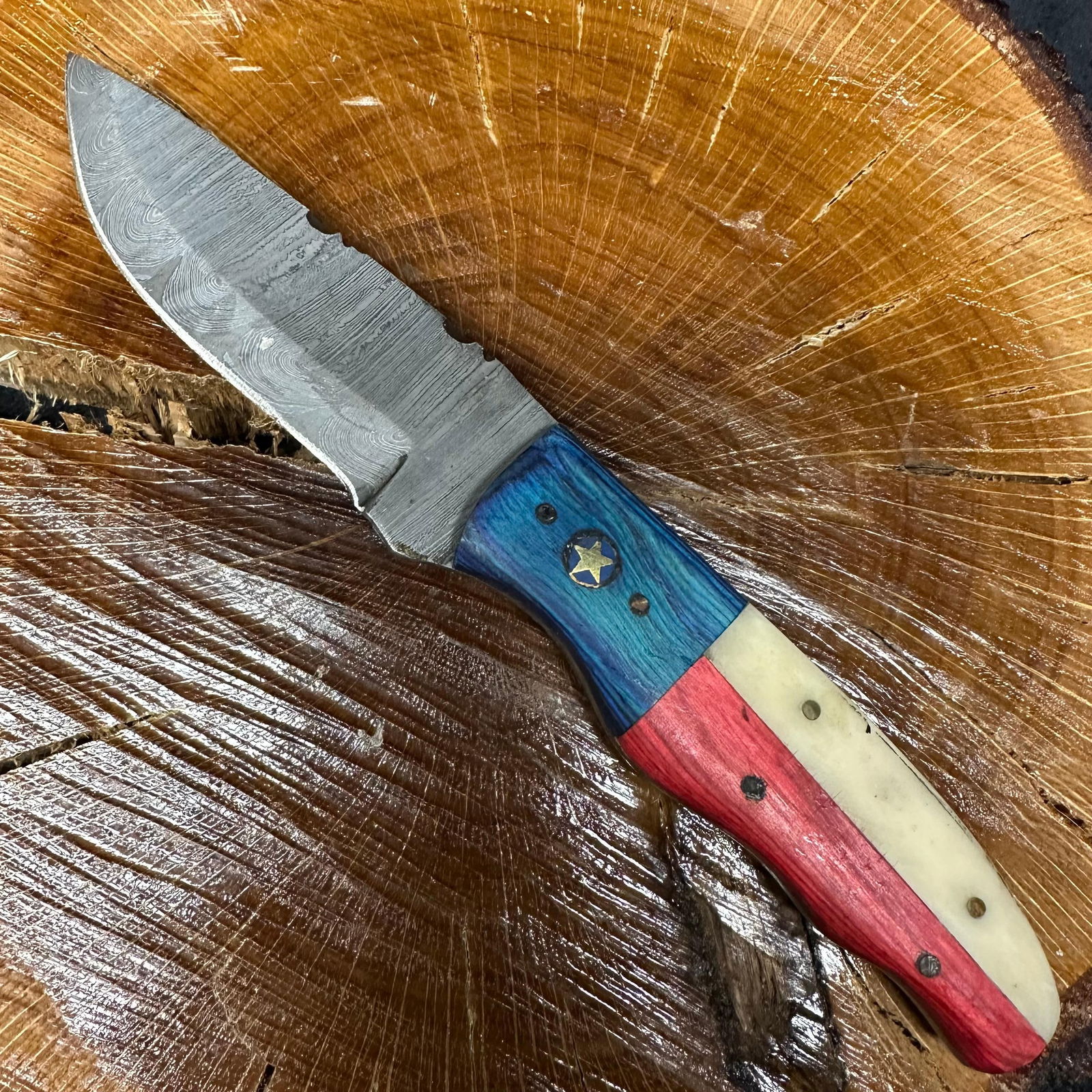 American Themed MHS Cutlery Steel Fixed Blade Knife with Brown Leather Sheath P62: Fixed blade knife by MHS Cutlery featuring a textured steel blade and decorative spine work. The handle has a contoured, red, white, and blue American-themed wood/resin-style grip with metal mosaic pi