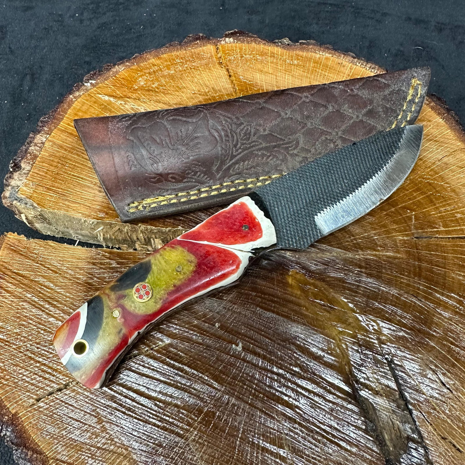 MHS Cutlery Steel Fixed Blade Knife with Brown Leather Sheath P61: Fixed blade knife by MHS Cutlery featuring a textured steel blade and decorative spine work. The handle has a contoured, multi-colored resin-style grip with metal mosaic pin accents. Includes a fitted