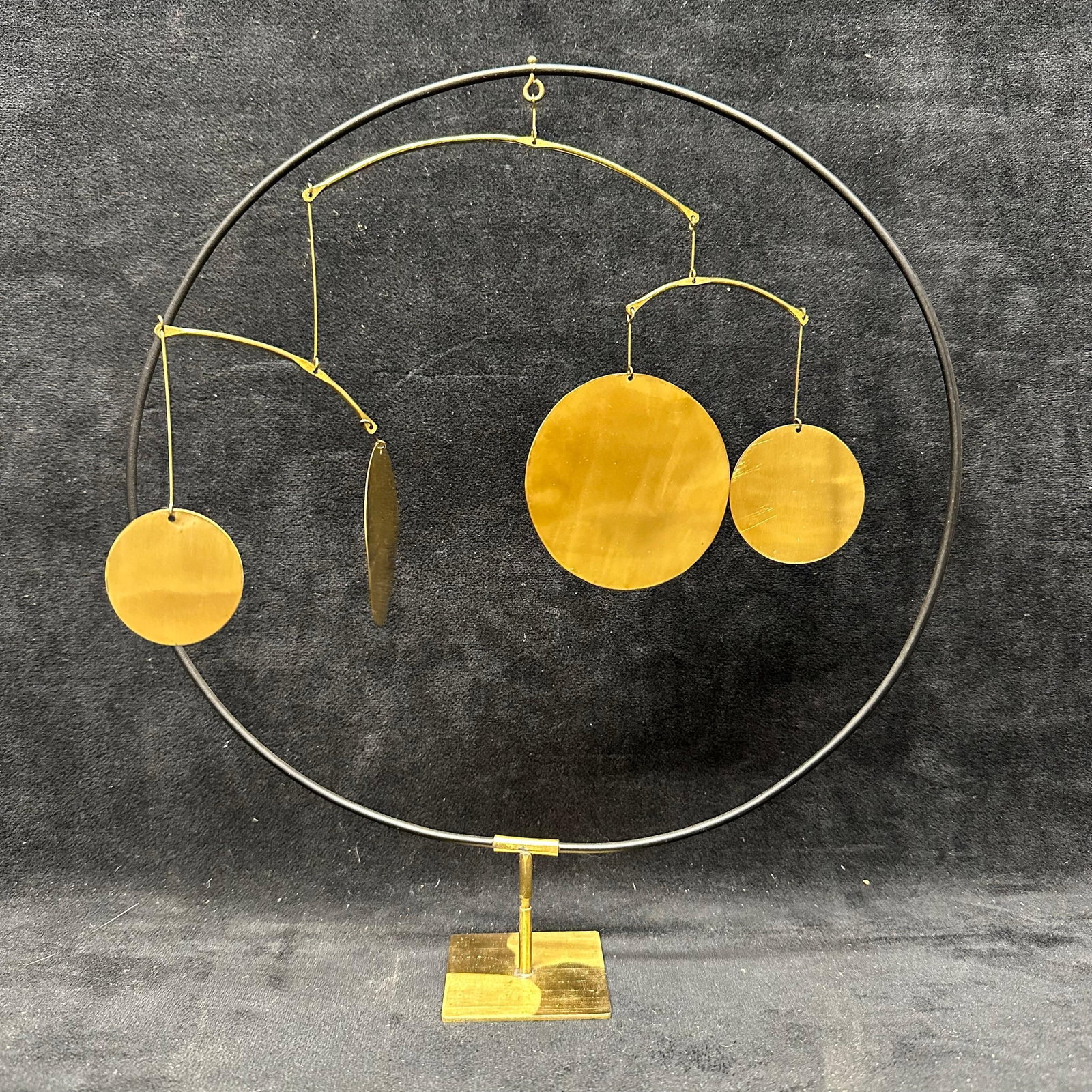 Decorative Kinetic Balance Sculpture with Brass Discs on Stand: Decorative tabletop kinetic balance sculpture featuring suspended circular and oval brass-toned discs arranged on curved metal arms within a circular frame. Mounted on a weighted rectangular base. Des