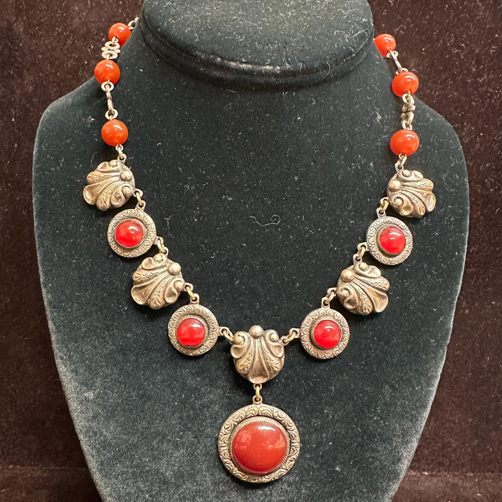 Vintage Silver-Tone Carnelian Necklace with Ornate Settings: Vintage necklace featuring multiple round cabochon stones in a rich red-orange hue, consistent with carnelian, set in ornate silver-tone bezels. Necklace design alternates between smooth round cabocho