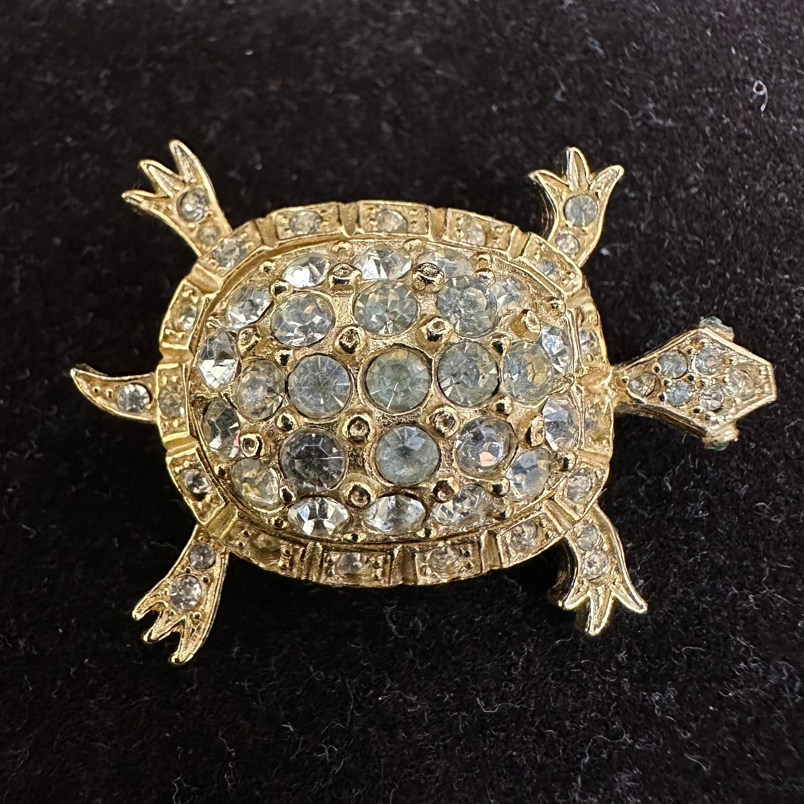 DeNicola Gold Tone Dimensional Turtle Brooch White Crystal Rhinestone Accents: Hallmark DeNicola on the back of the gold-toned brooch featuring clear and green rhinestone accents. This item is in good pre-owned, previously displayed condition with light wear and surface scratche