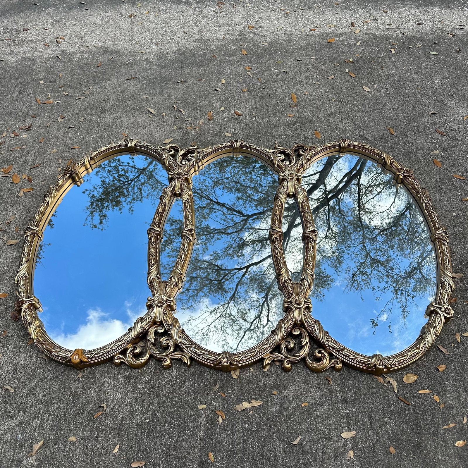 Vintage Bassett Mirror Co. Triple Oval Gold Gilt Wall Mirror: Large vintage triple-panel wall mirror by Bassett Mirror Co., Bassett, Virginia. Features three connected oval mirrors within an ornate gold-tone molded frame with scrolling acanthus leaf and floral d