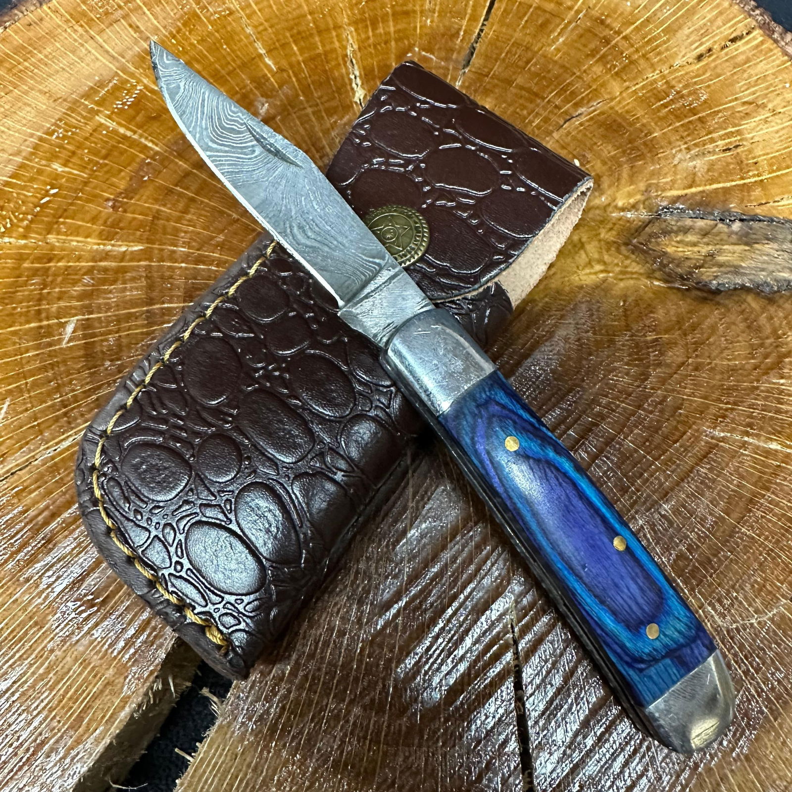MHS Cutlery Steel Folded Blade Pocket Knife Blue Design Handle with Sheath Q94: Folding blade pocket knife by MHS Cutlery featuring a layered patterned steel blade and decorative spine work. The decorative handle has a contoured, blue wood/resin-style grip with metal mosaic pin a