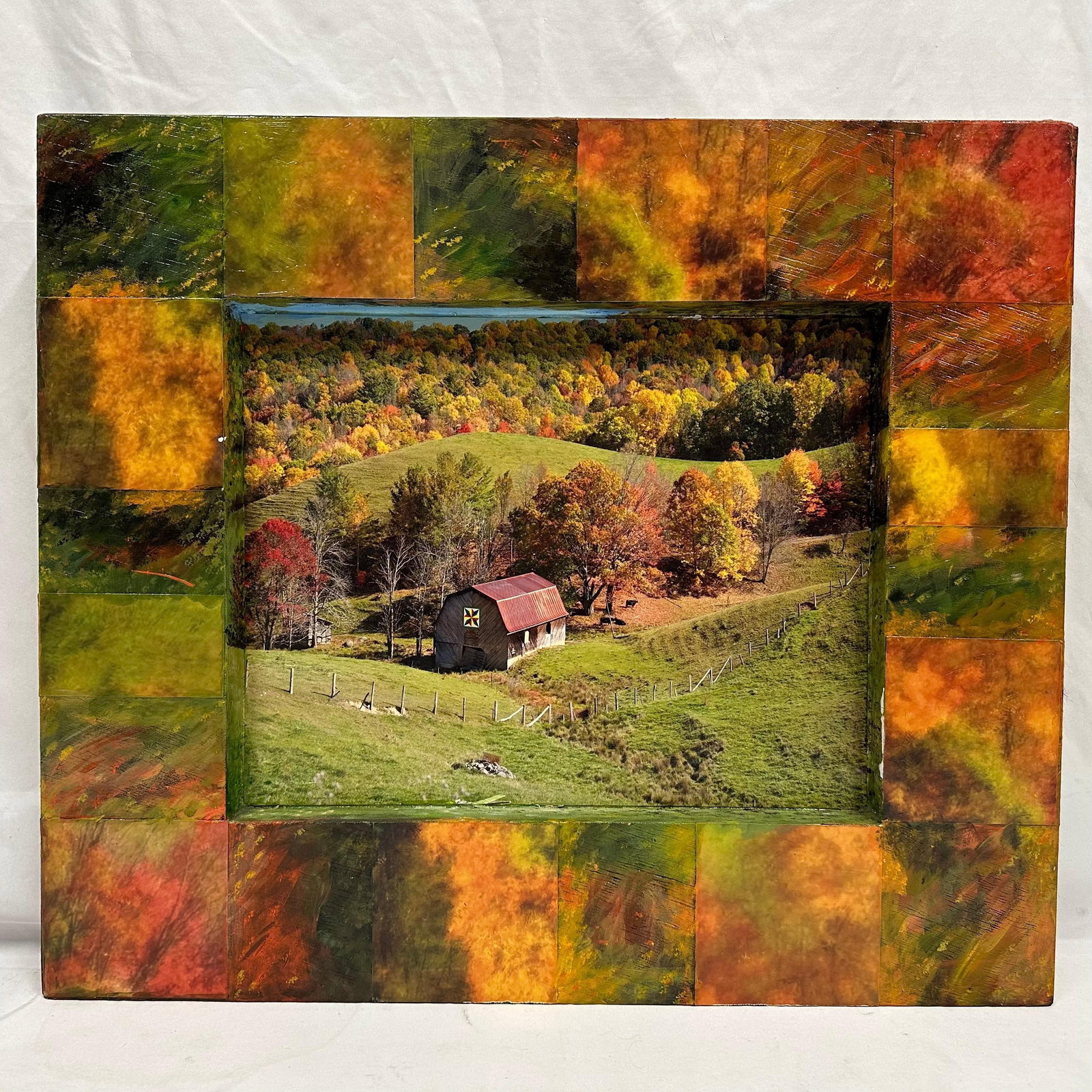 Robert Stein Barn with Quilt Block Mixed Media Wall Relief Wood Artwork: Mixed media wall relief by Robert Stein depicting a rural barn set within rolling farmland and autumn foliage. Central photographic image is recessed and surrounded by hand-painted, textured panels in