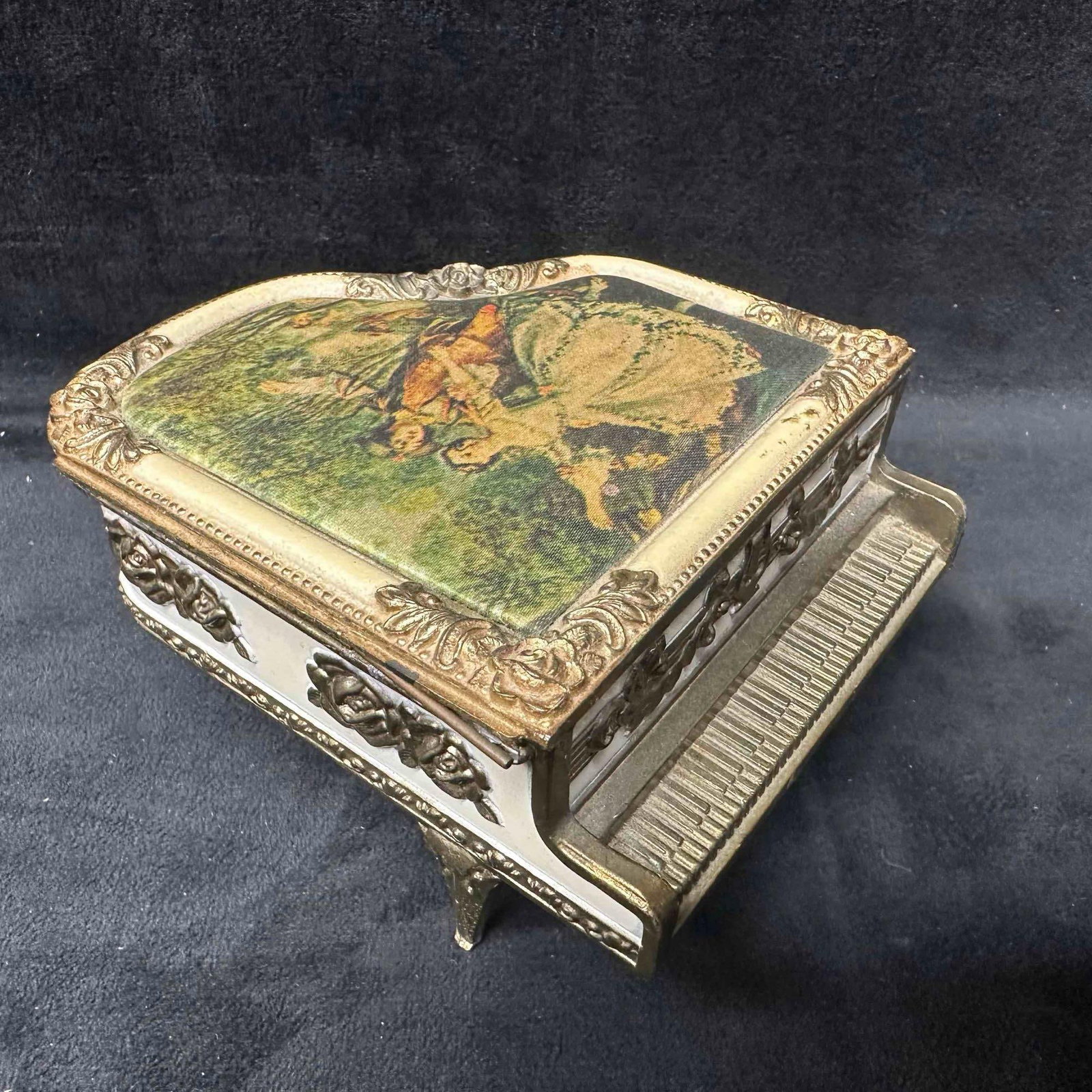 Decorative Metal Grand Piano Music Box Hi Mark Japan Ornate Design Needs Repair: Vintage grand piano-shaped music box with ornate raised floral and scroll details, white enamel sides, and a framed pastoral scene on the hinged lid (broken). Interior features red felt lining and a p