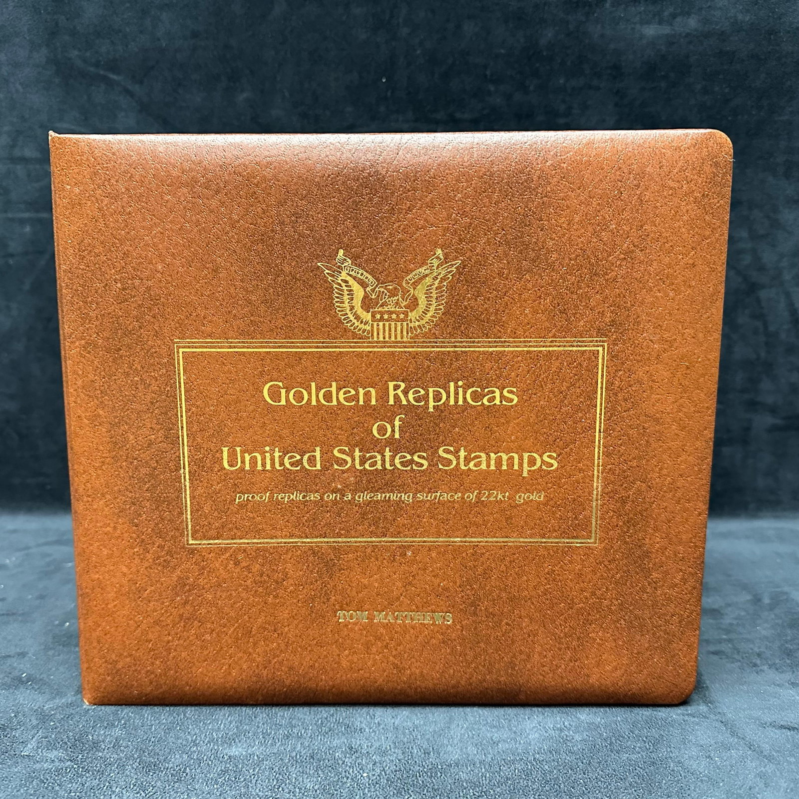 Golden Replicas of United States Stamps Postal Commemorative Society Album: Bound presentation album titled Golden Replicas of United States Stamps issued by the Postal Commemorative Society. The album contains official First Day Covers paired with gold-embossed stamp replica