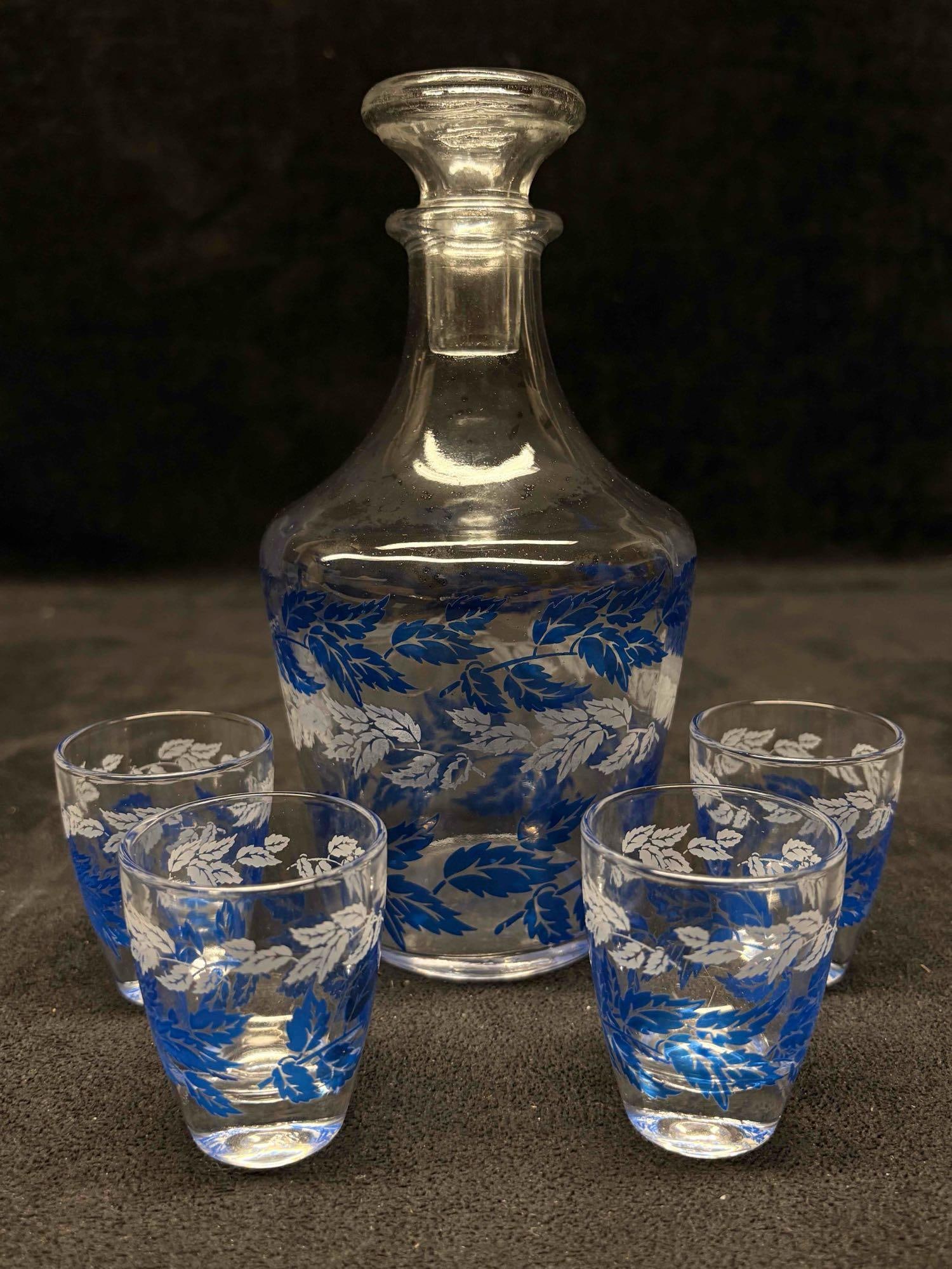 5pc French Vintage Luminarc Glass Liquor Decanter Set: This lot includes the Luminarc glass decanter set from France, typically dated to the 1970s . This barware set is recognized by its distinctive blue and white leaf decal pattern on clear glass. The lo