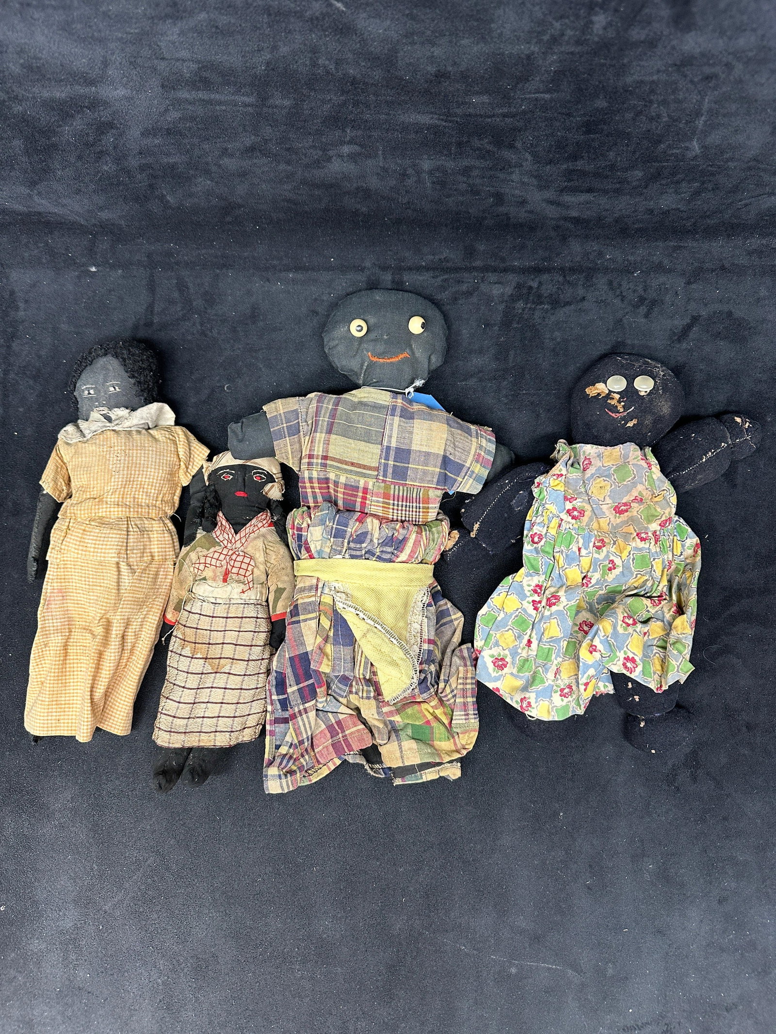 Antique Hand Made Black Americana Cloth Dolls Group of Four: Group of four antique handmade Black Americana cloth dolls featuring hand-stitched facial details, button eyes, and yarn or fabric hair. Dolls are dressed in period-style patterned garments, including
