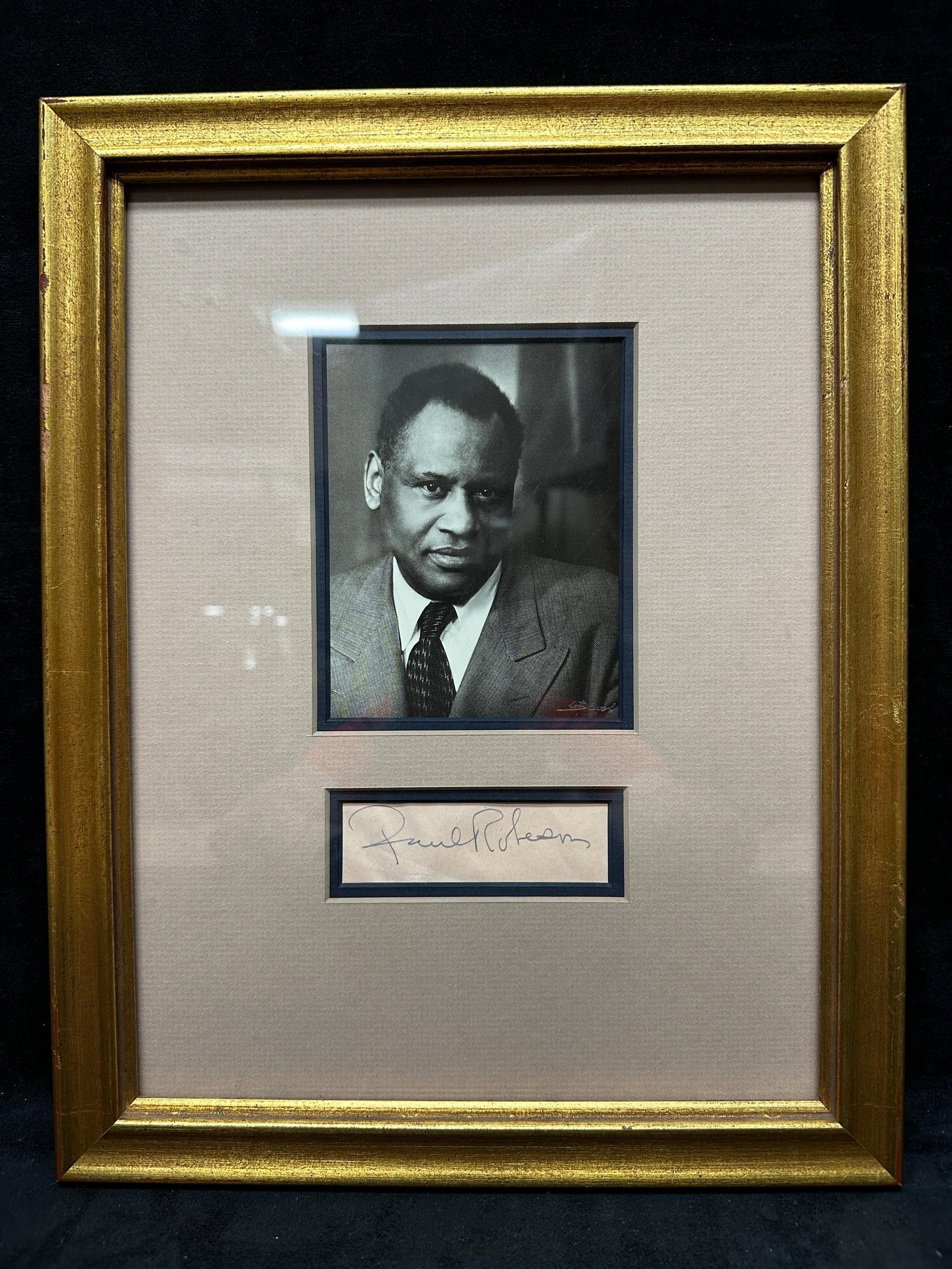 Paul Robeson Signed Autograph Framed With Portrait Photograph: Framed display featuring a signed autograph of Paul Robeson, American singer, actor, and civil rights figure, presented below a black and white portrait photograph. Signature appears in ink on paper a