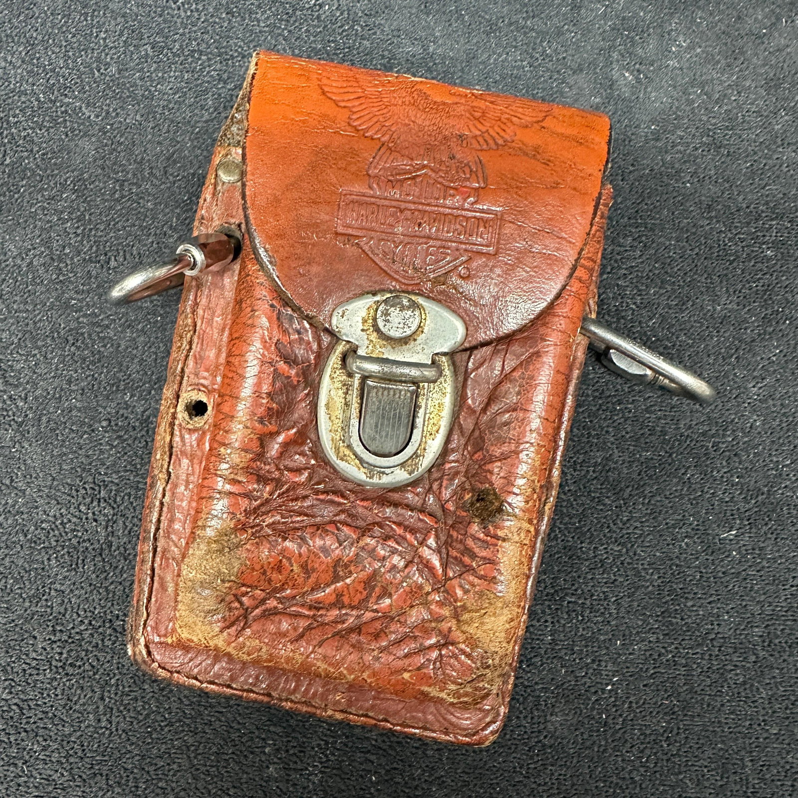 Harley Davidson Leather Motorcycle Cigarette Tool Bag Case: Harley Davidson leather motorcycle tool bag with embossed eagle and Harley Davidson Motorcycles logo. Features a metal clasp closure and mounting hardware loops. Showing heavy wear, scuffs, cracking, 